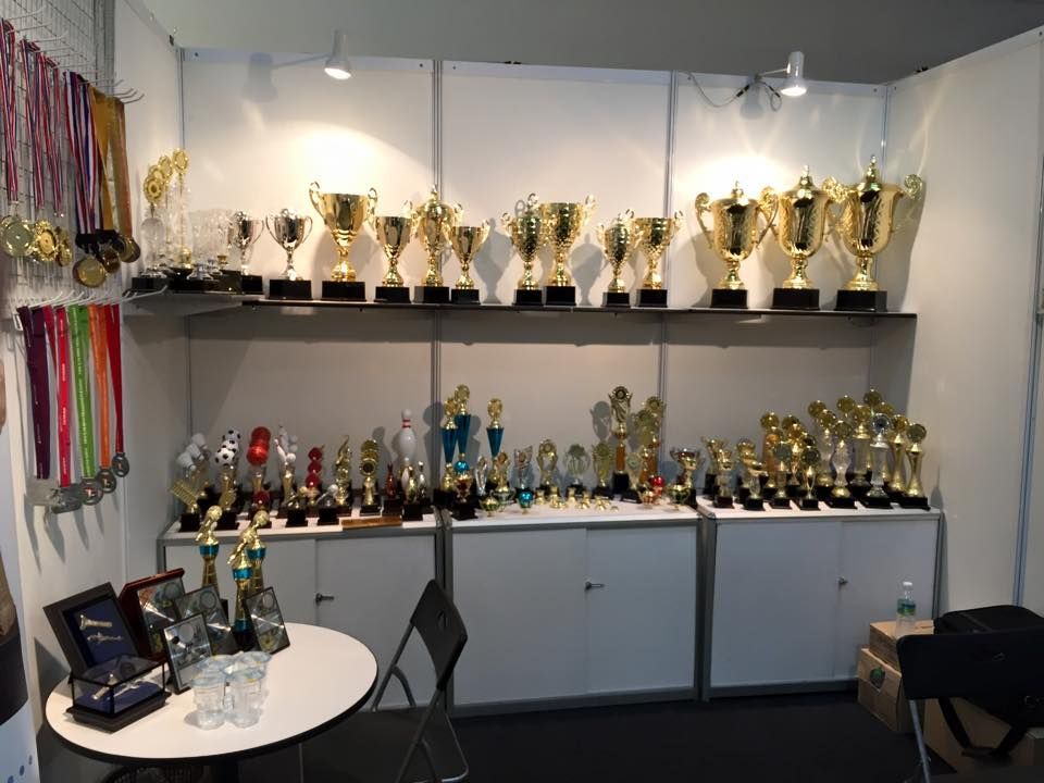 Baguss Enterprise booth at Malaysia Gifts Expo 2016, Shah Alam Convention Centre — showcasing trophies and medals.