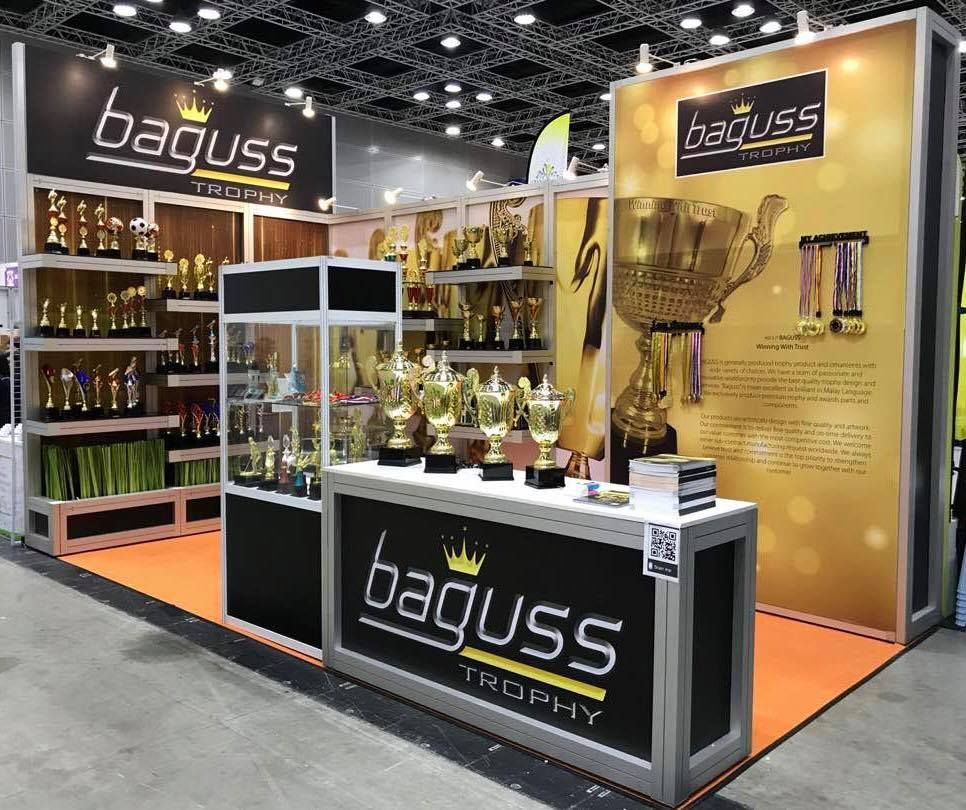 Baguss Enterprise booth at MGF 2018, KLCC — trophies displayed inside a glass cabinet and on racks