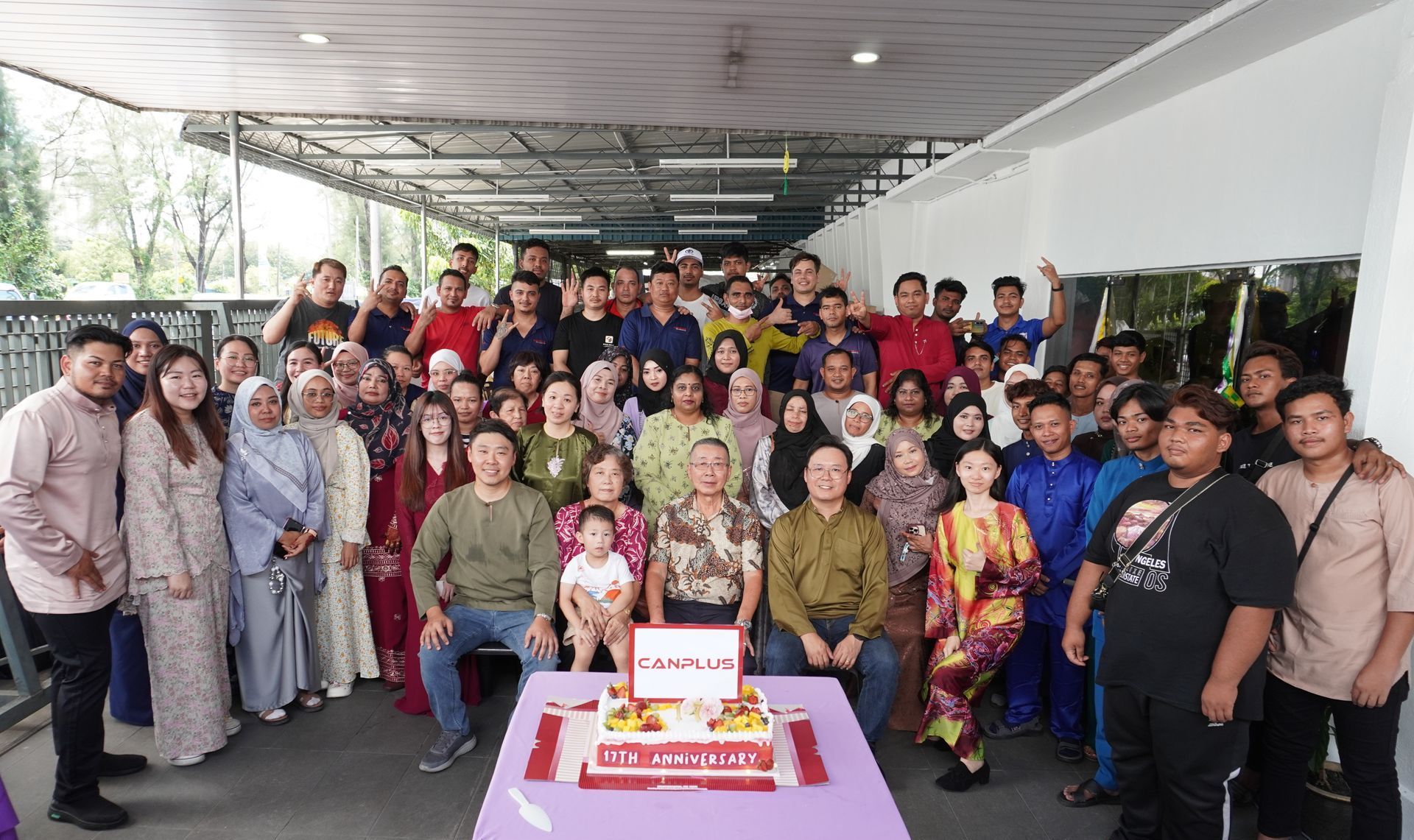 Large group photo of all employees with the boss, smiling and enjoying the Raya gathering together at the company event.