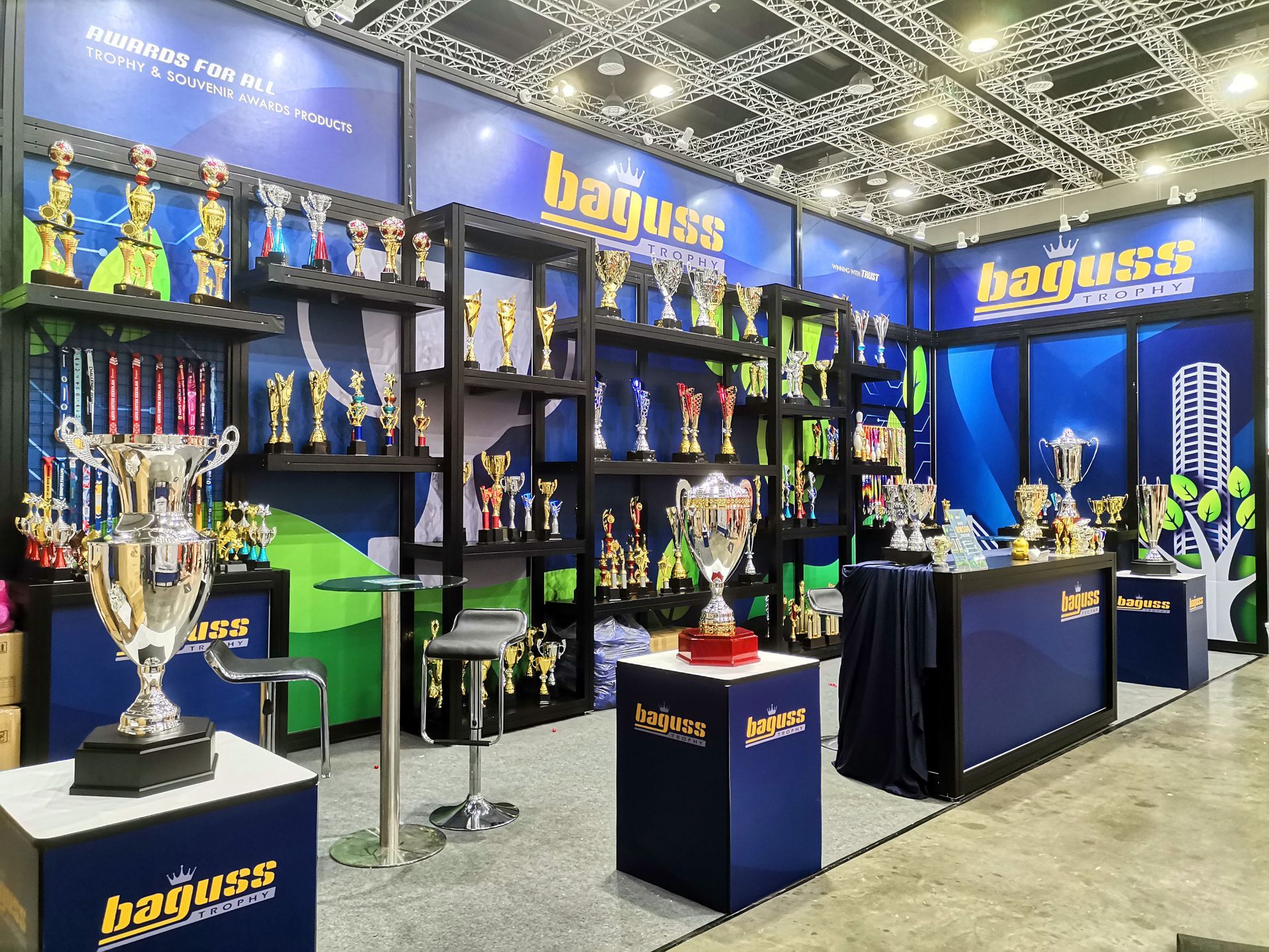 Full view of Baguss Enterprise booth at MGF 2024, KLCC — featuring four giant trophies and a wide display of products.