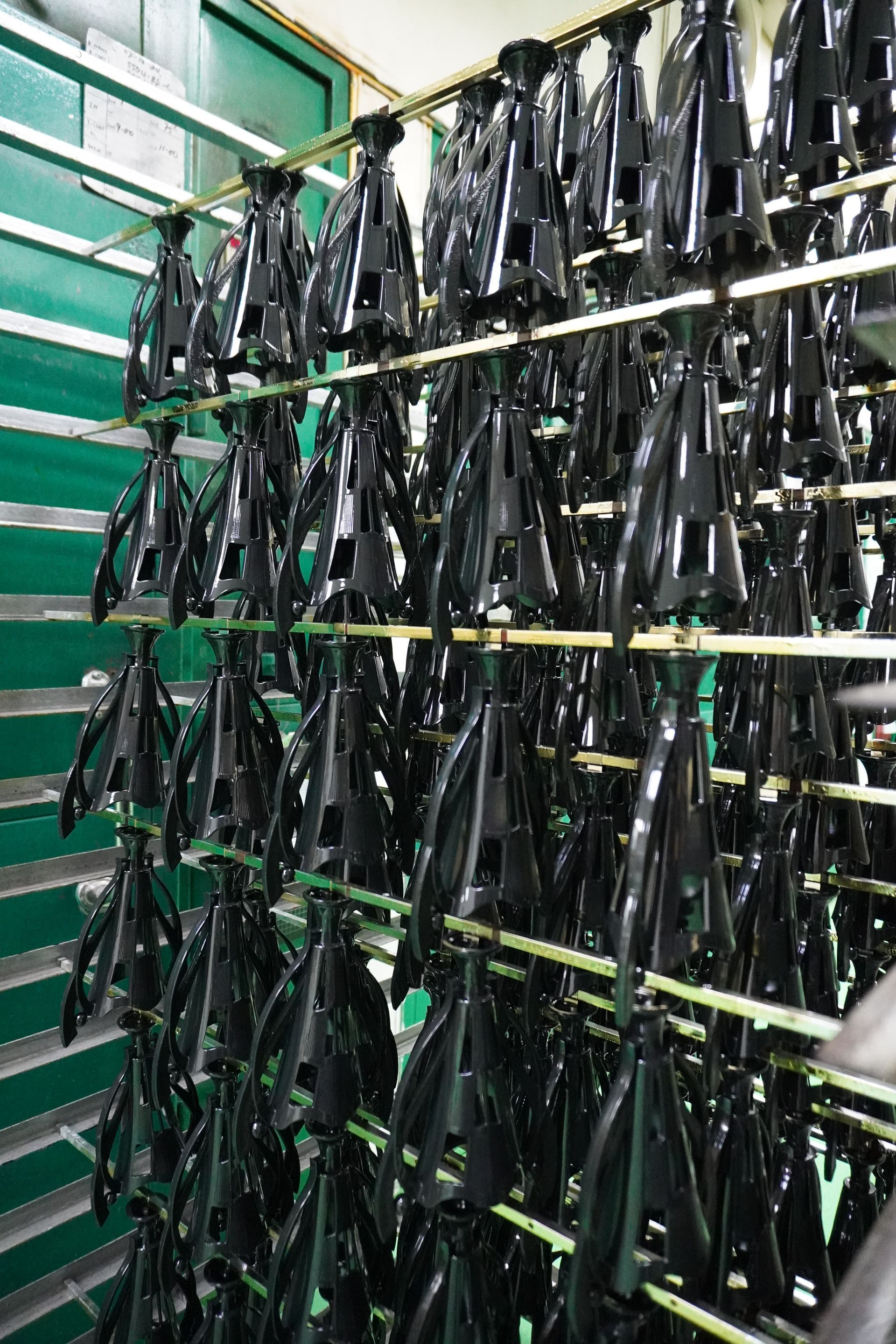 Trophy parts hanging on metal rods in production, ready for chroming process at Baguss Enterprise.