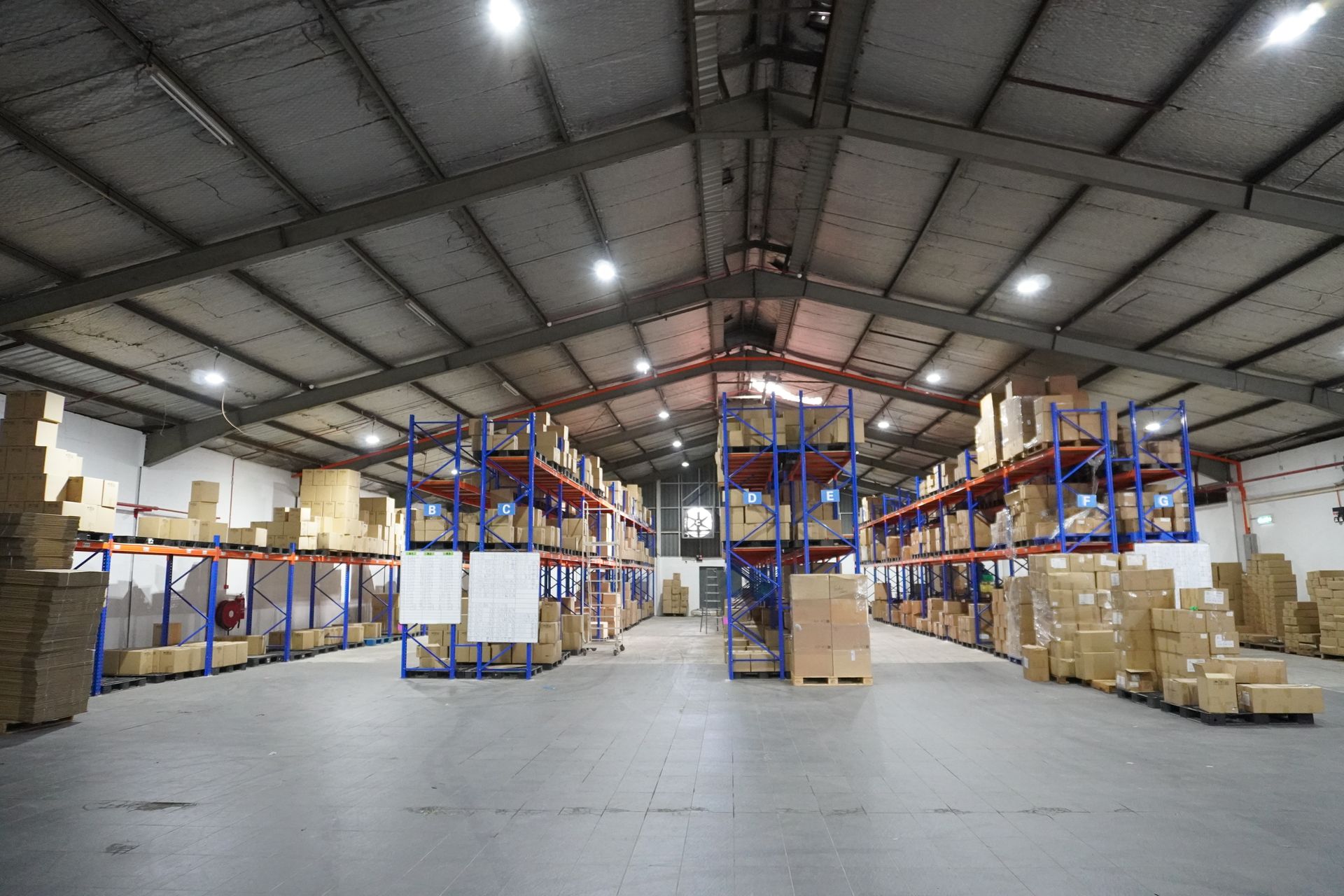 Wide view of warehouse space with shelves stocked with trophy parts, medals, and packaging materials.