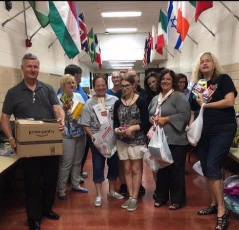 A group of people standing in a hallway holding bags and a box that says pink puppy