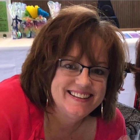 A woman wearing glasses and a red shirt is smiling