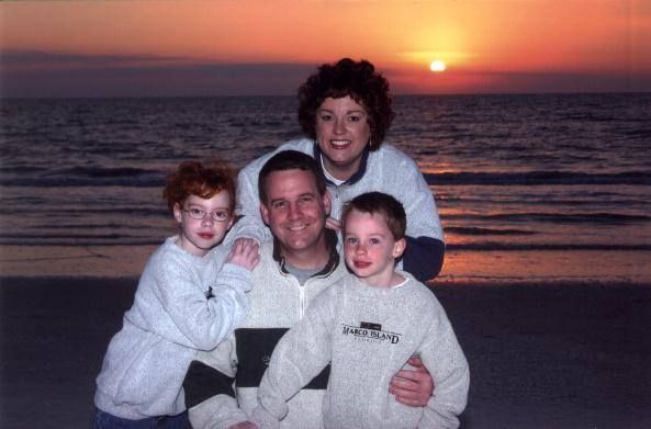 A family poses for a picture on the beach at sunset