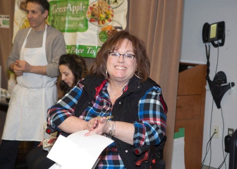 A woman is sitting in front of a sign that says green apple