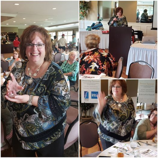 A woman in a floral shirt is holding a trophy