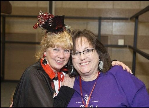 Two women posing for a picture with one wearing a purple shirt