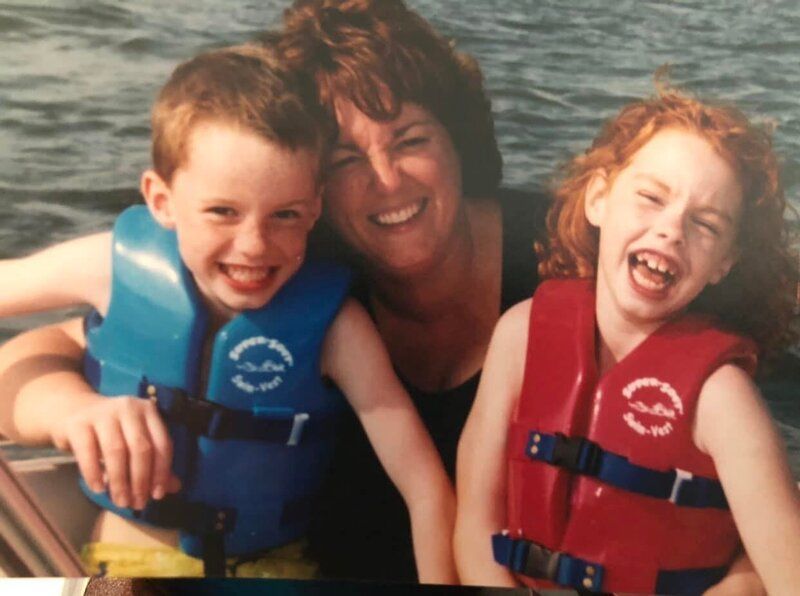 A woman and two children wearing life jackets on a boat