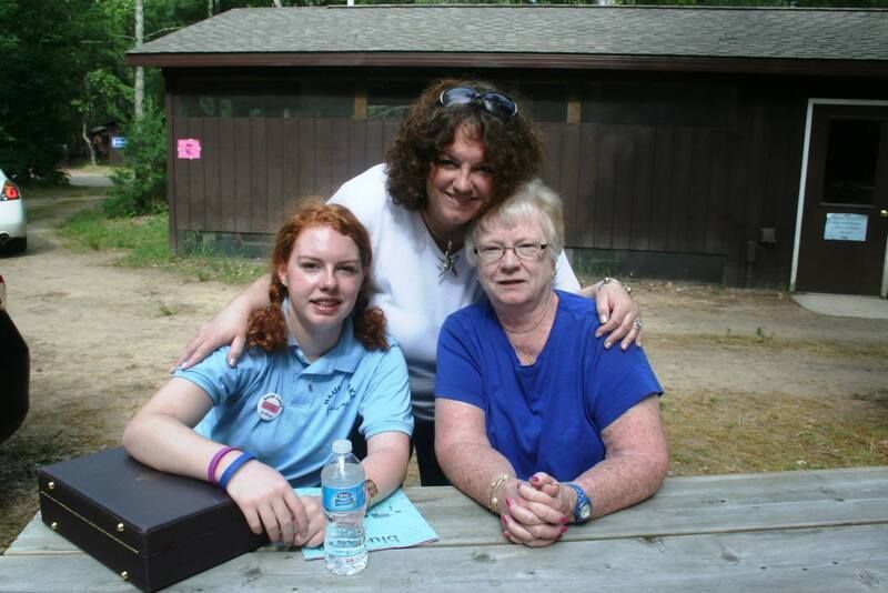 Three women sitting at a picnic table with a bottle of aquafina water