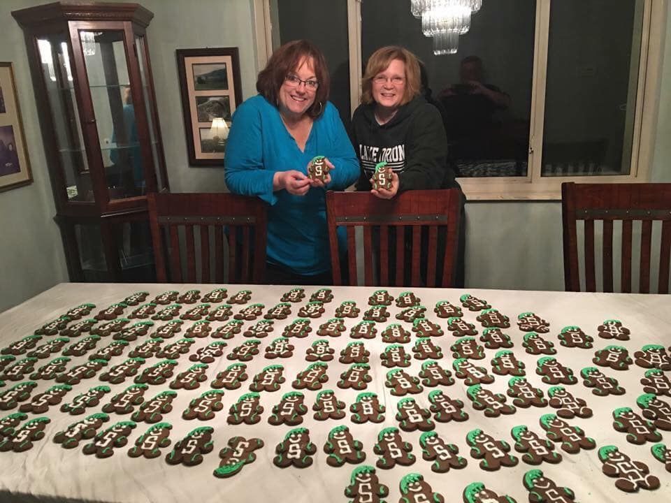 Two women are standing in front of a table full of cookies