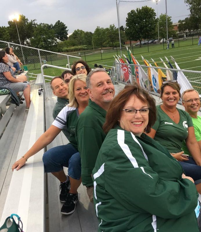 A group of people are sitting on bleachers at a football game