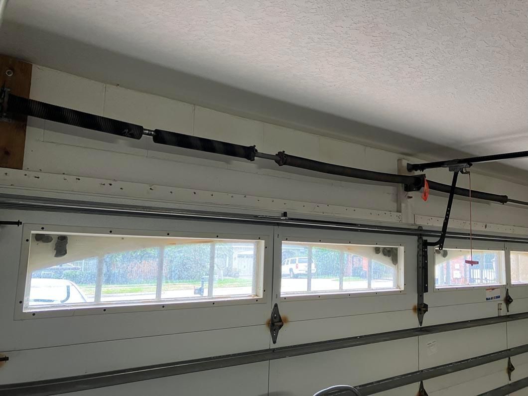 Interior of a garage with a sectional door, windows, and a ceiling-mounted opener track.