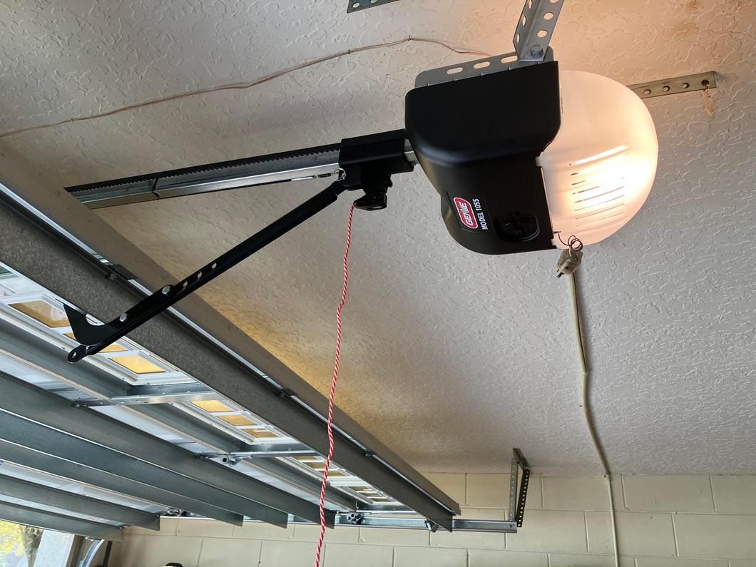 Garage ceiling with a black garage door opener and metal track rails hanging overhead