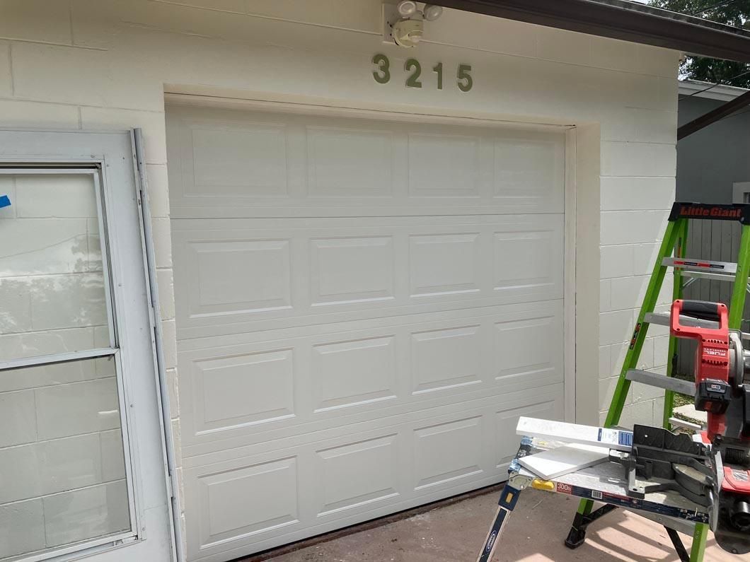 White garage door with house number 3215 and a ladder, workbench, and tools in front