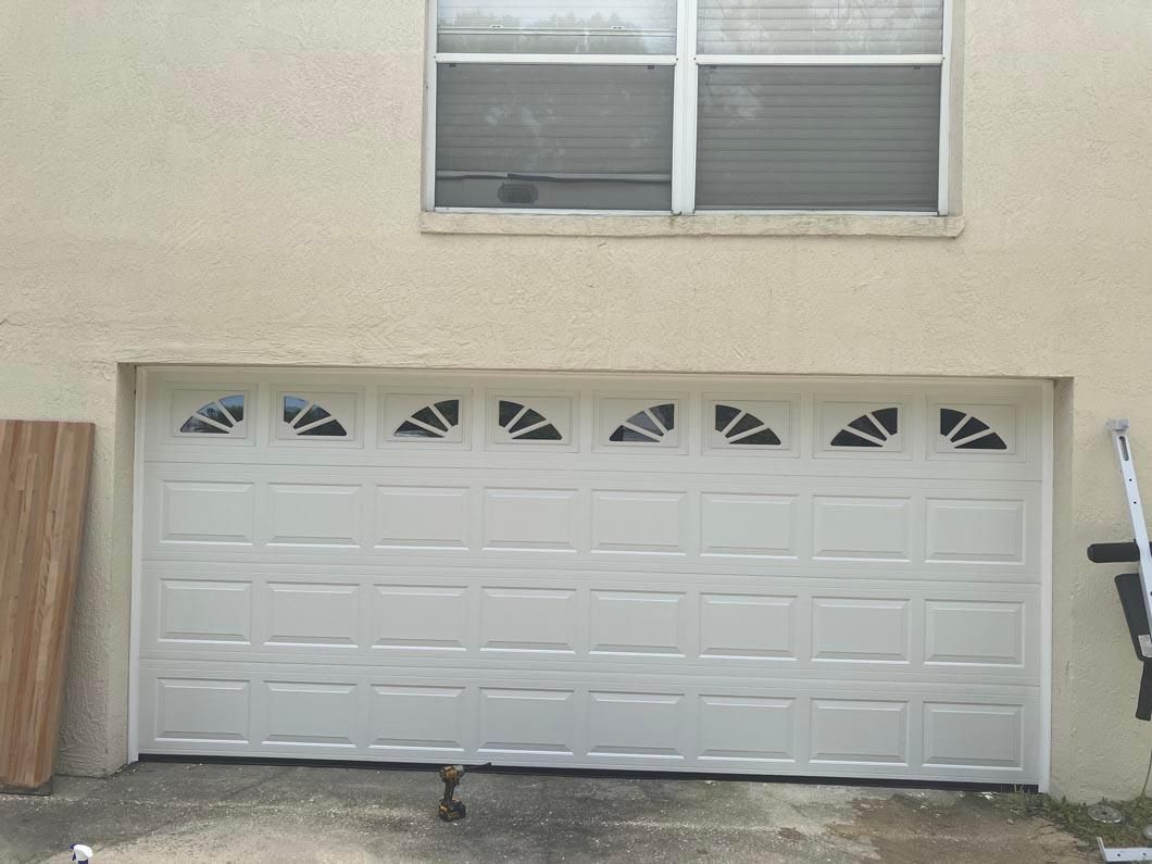 White double garage door on beige house exterior with two upstairs windows.