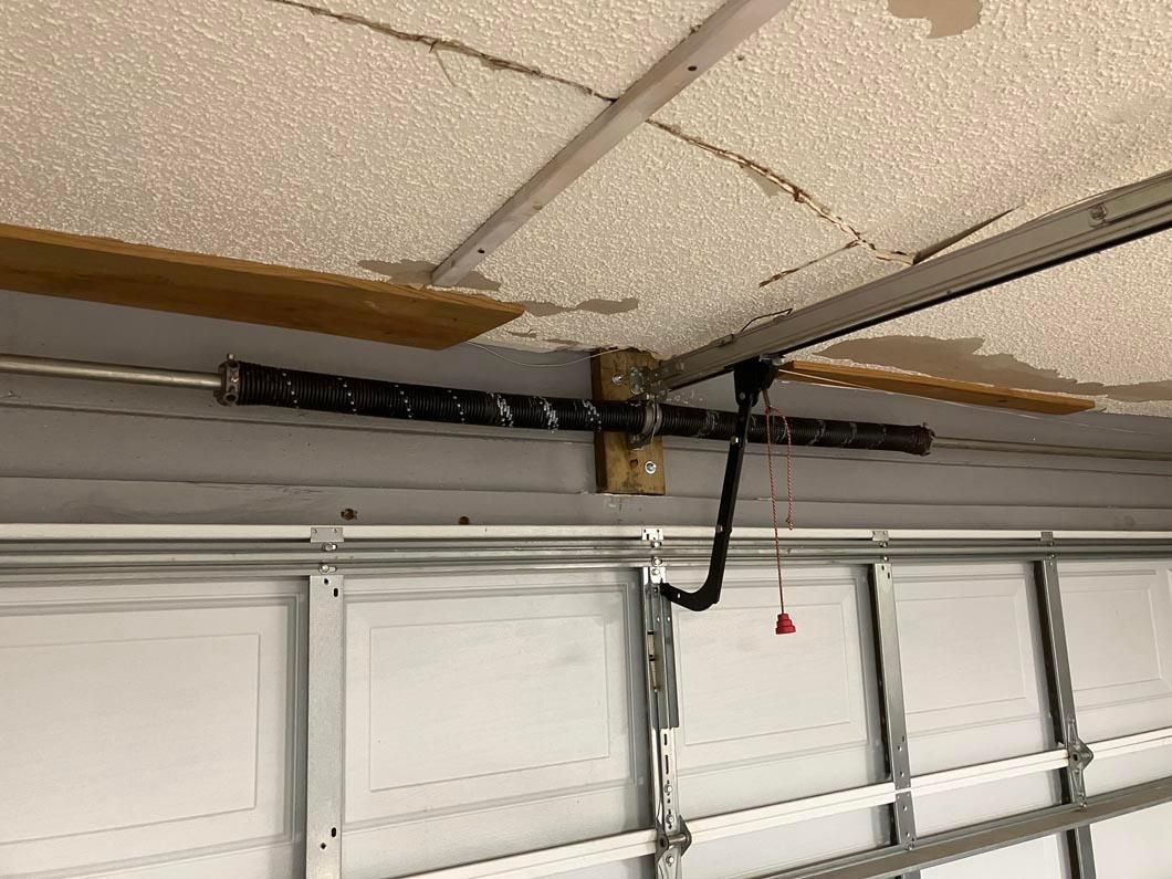 Garage door opener mounted on a ceiling with exposed mechanism and hanging pull cord