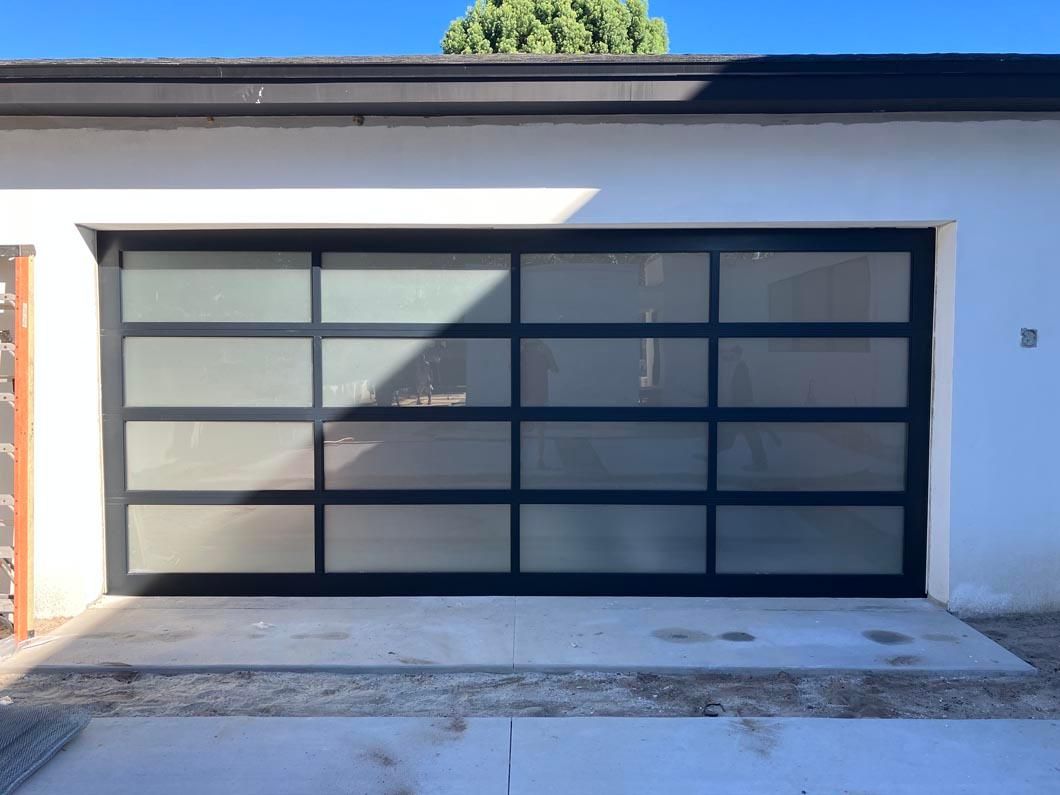 Modern house garage with frosted glass door and white stucco exterior, seen in daylight