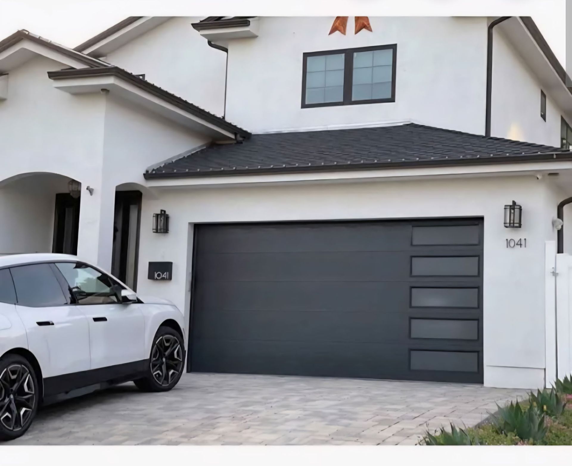 Modern white house with dark gray garage door and a white SUV parked in the driveway