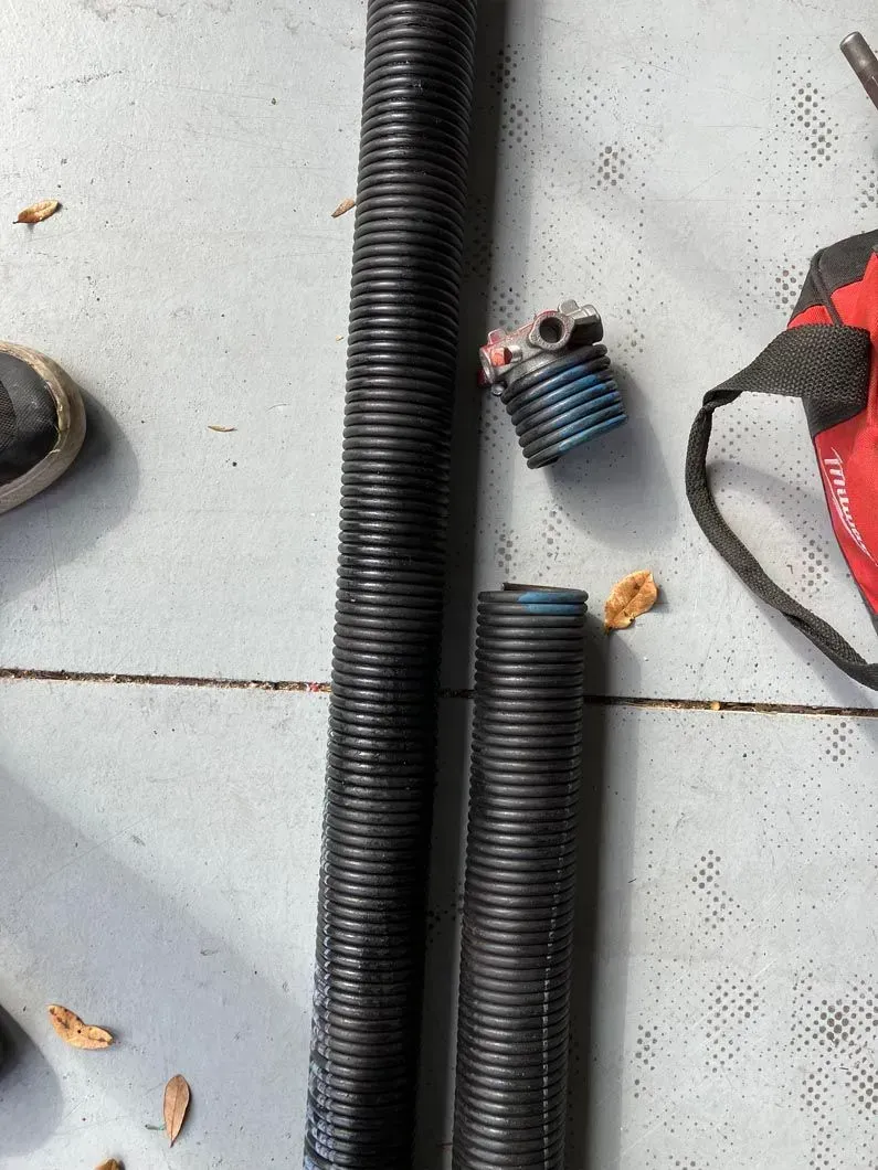 Black corrugated hoses and a small blue fitting on a gray floor with scattered debris