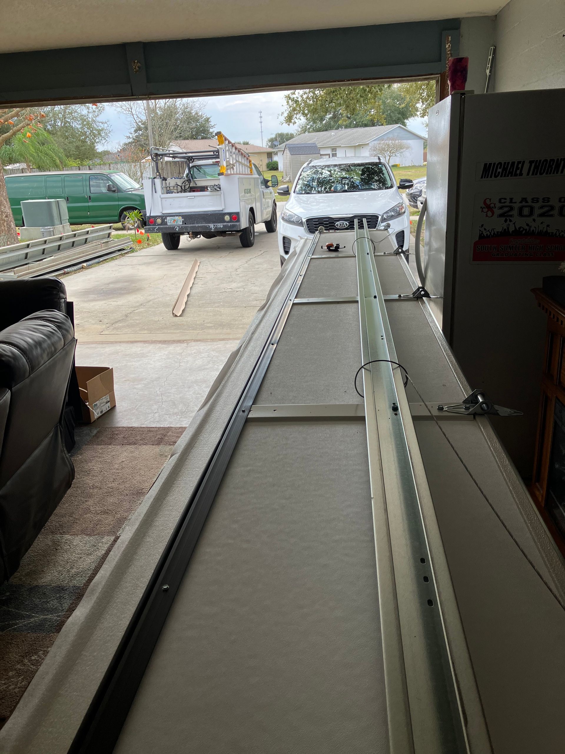 Conveyor belt leading from a garage to a white utility truck parked outside.