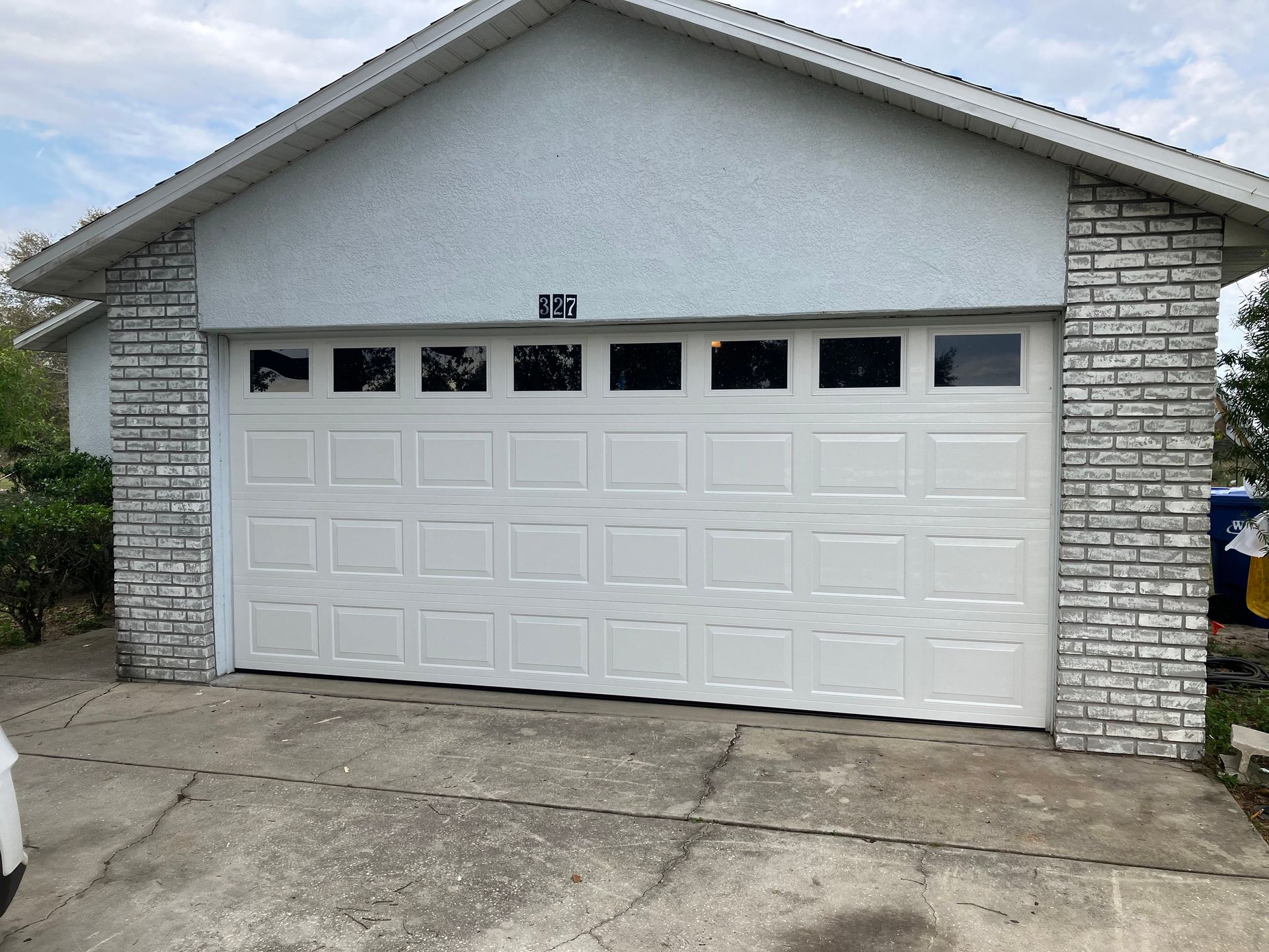 White garage with stone side pillars and a closed two-car garage door under a gray roof.