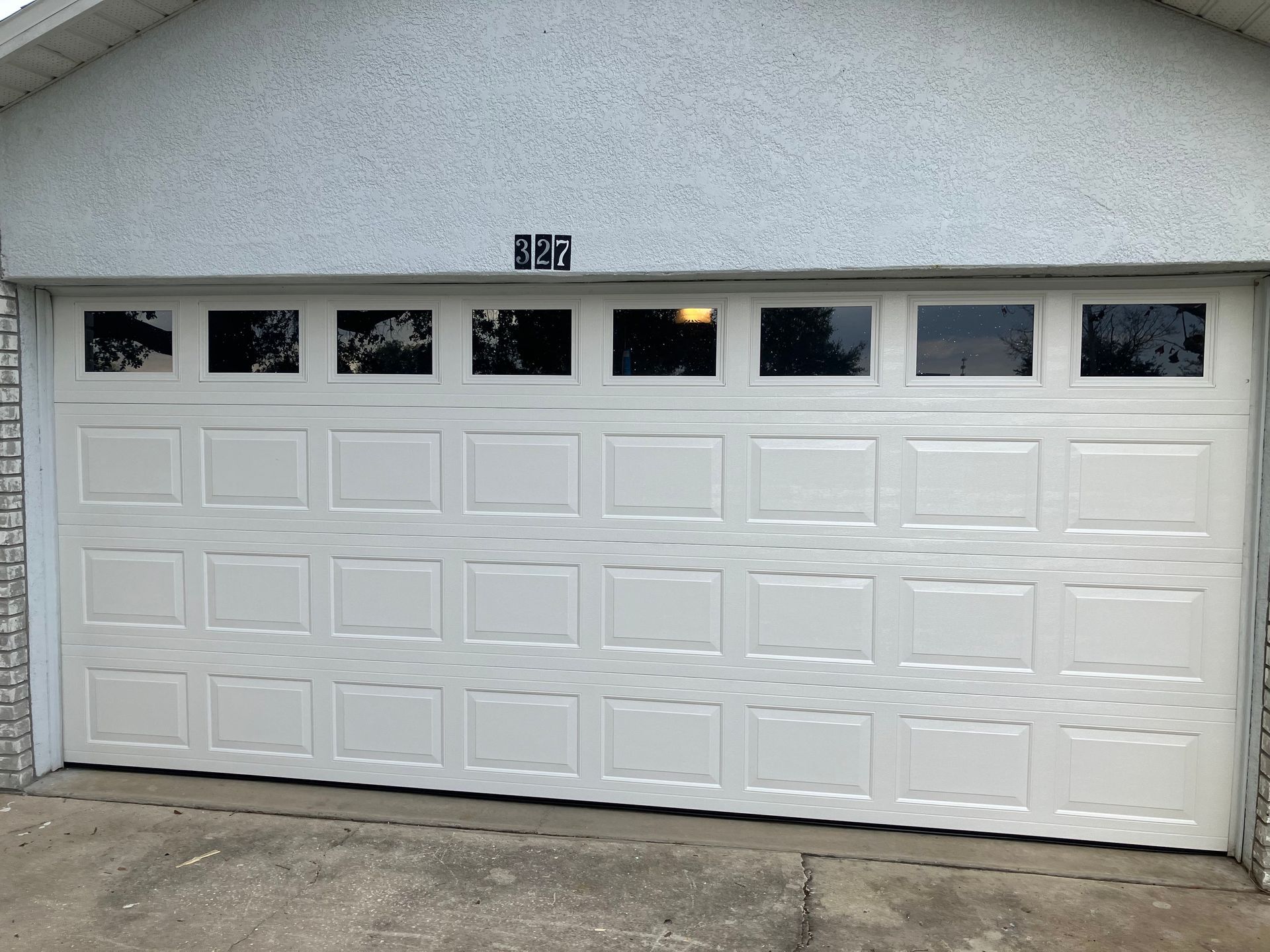 White garage door with small windows on a stucco house exterior