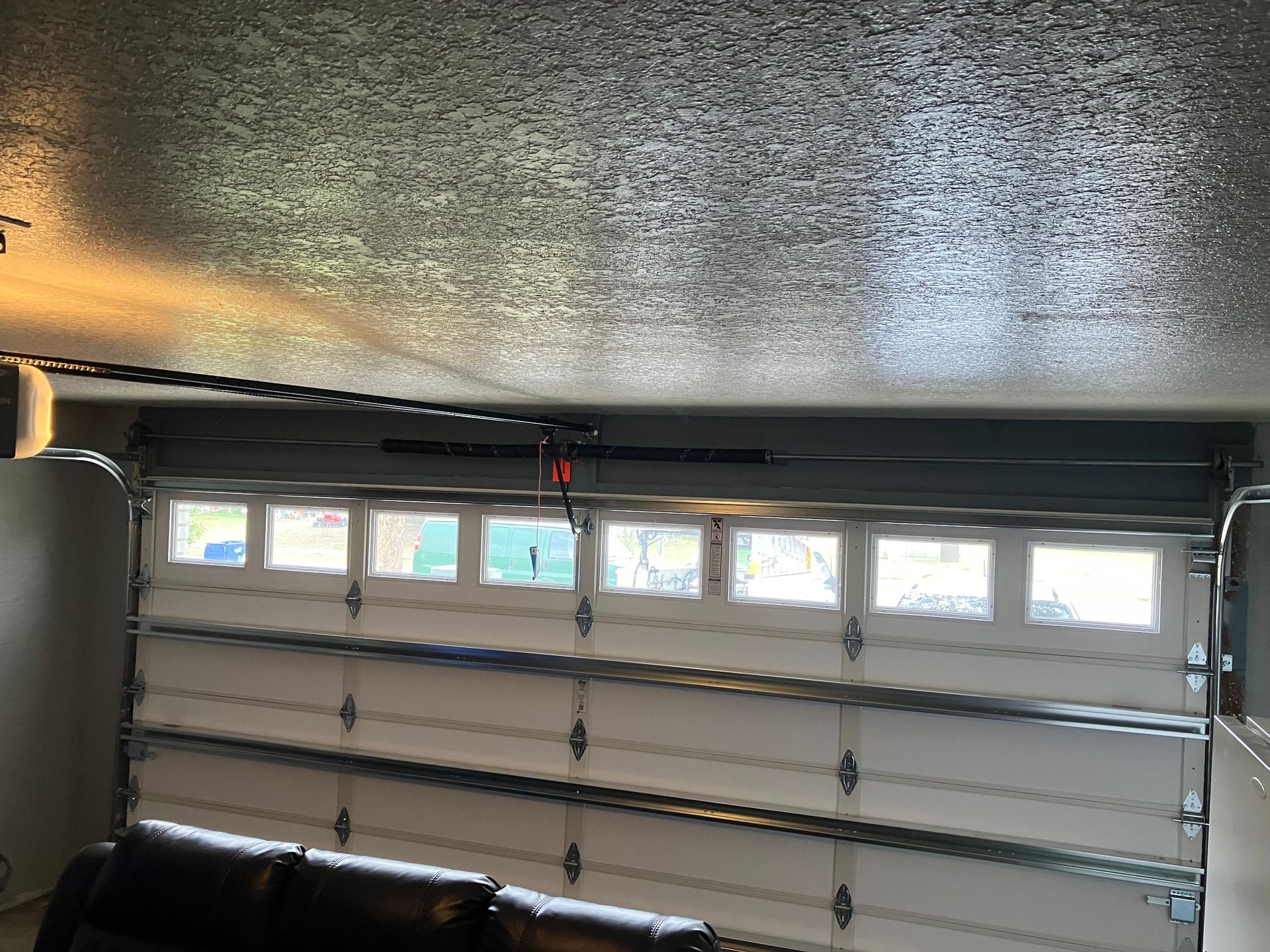 Interior of a garage with a closed white sectional door and small windows near the top.