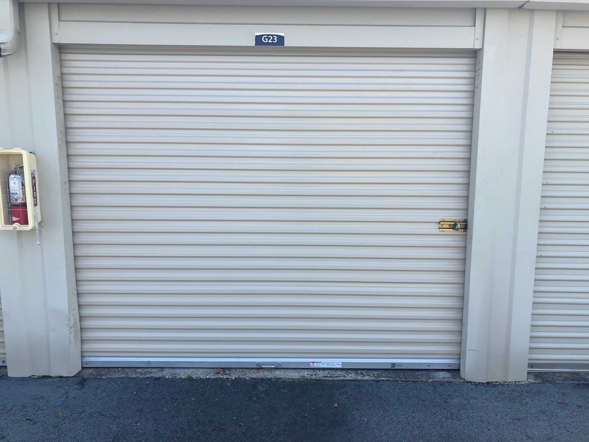 Closed beige roll-up garage door in a storage unit row
