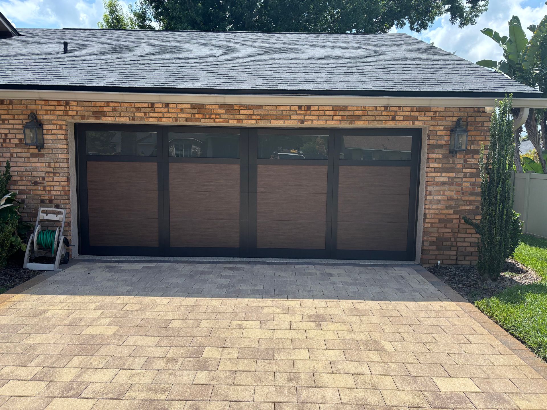 Brick house garage with a closed dark brown three-car door and a paved driveway