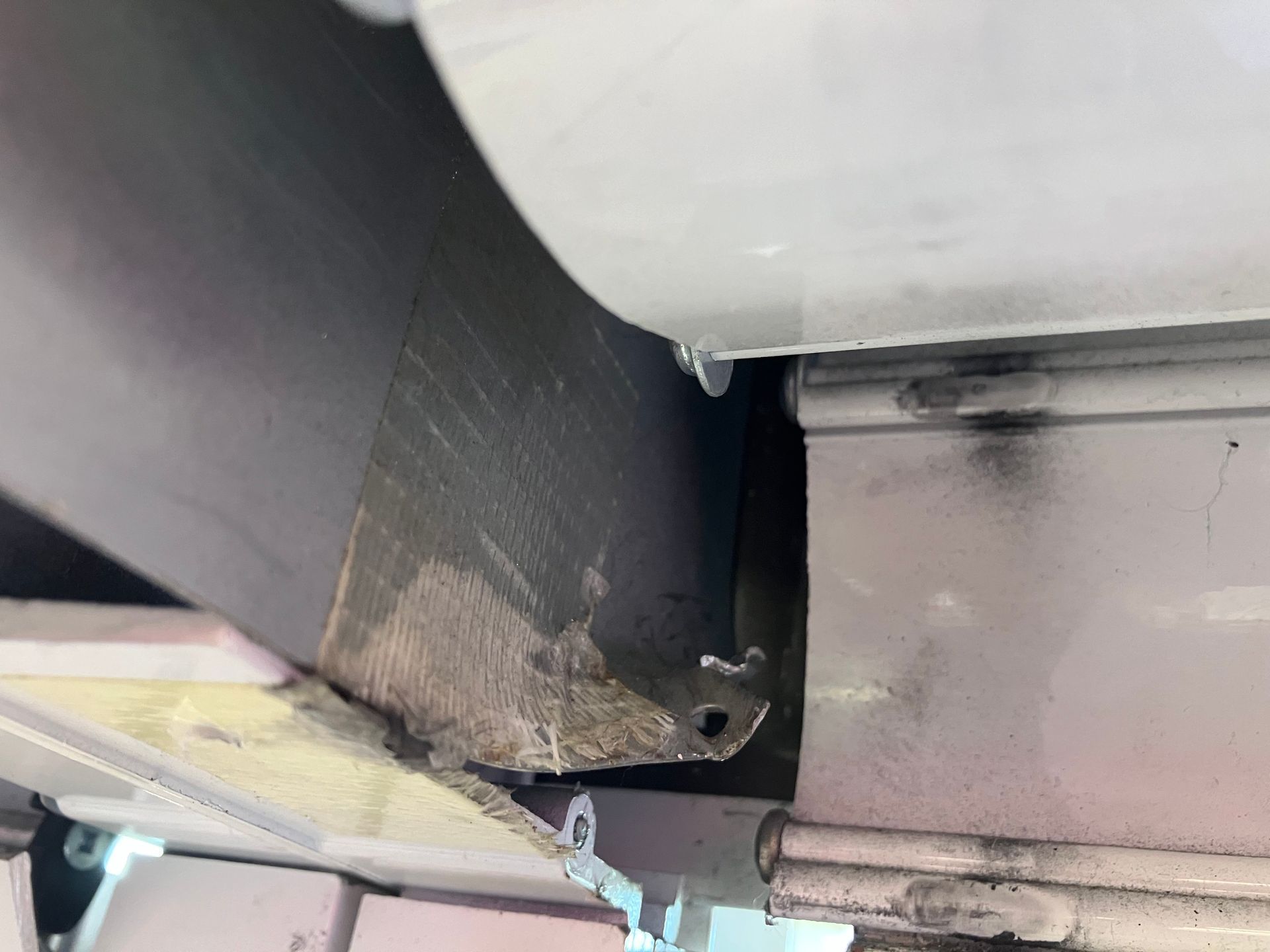 Damaged black metal beam with chipped edge beside a gray structural component