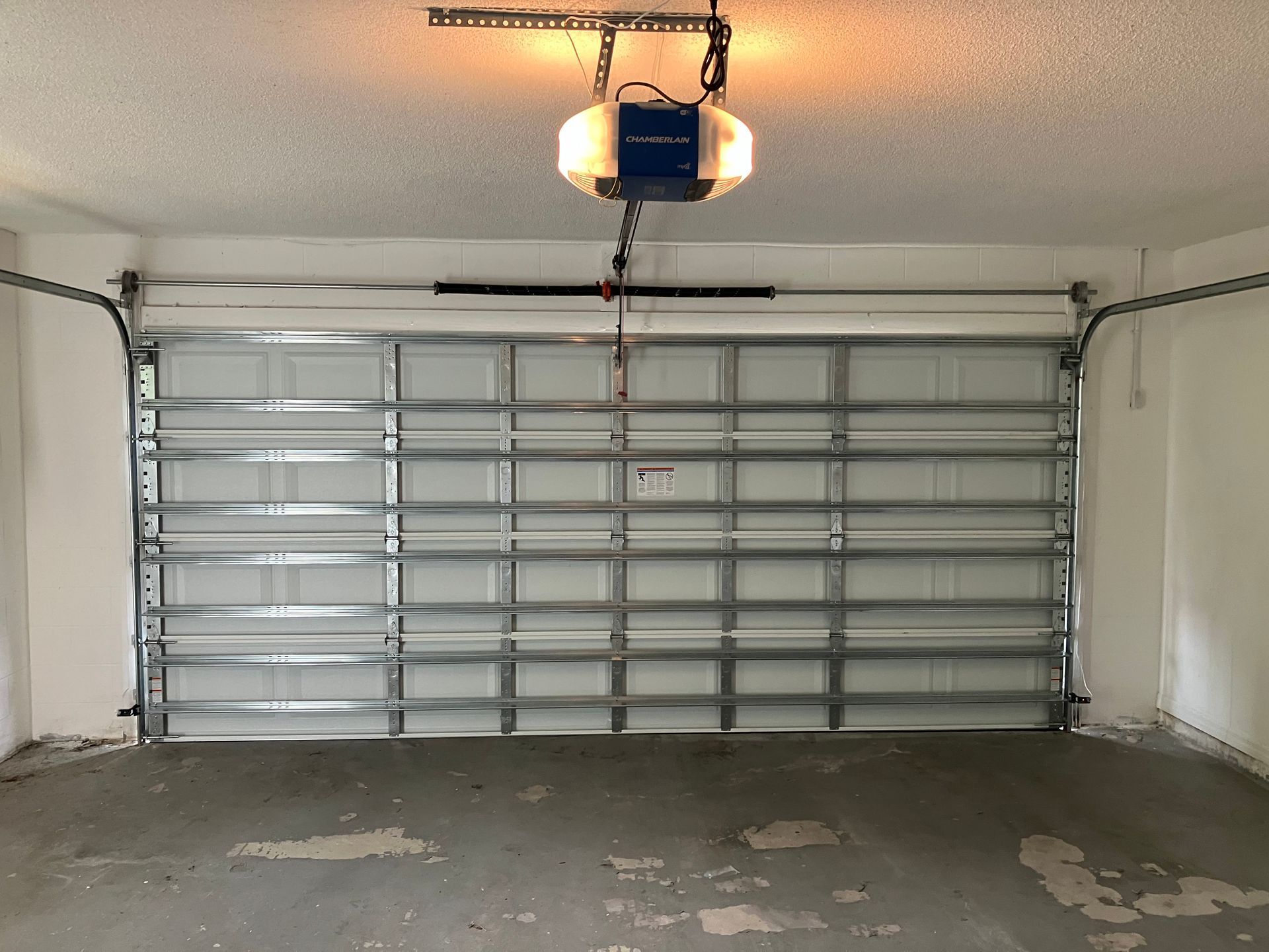Garage interior with closed metal sectional door and concrete floor under a ceiling light