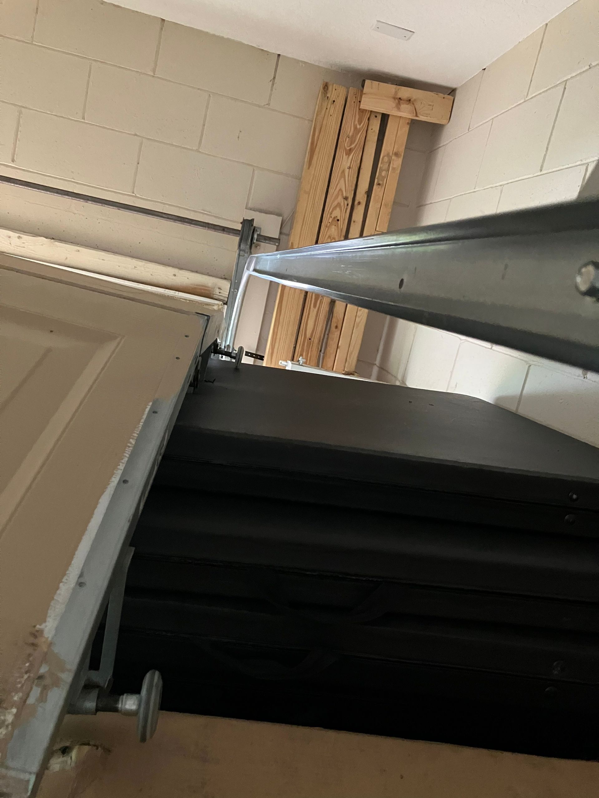 Tilted view of a stairwell with metal railings, white cinderblock wall, and wooden supports.