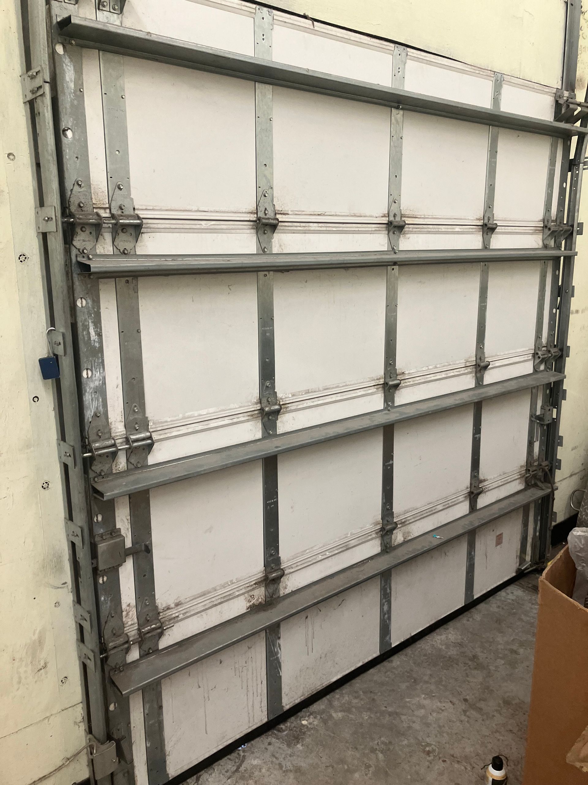 White sectional garage door with metal braces, viewed from inside a garage.