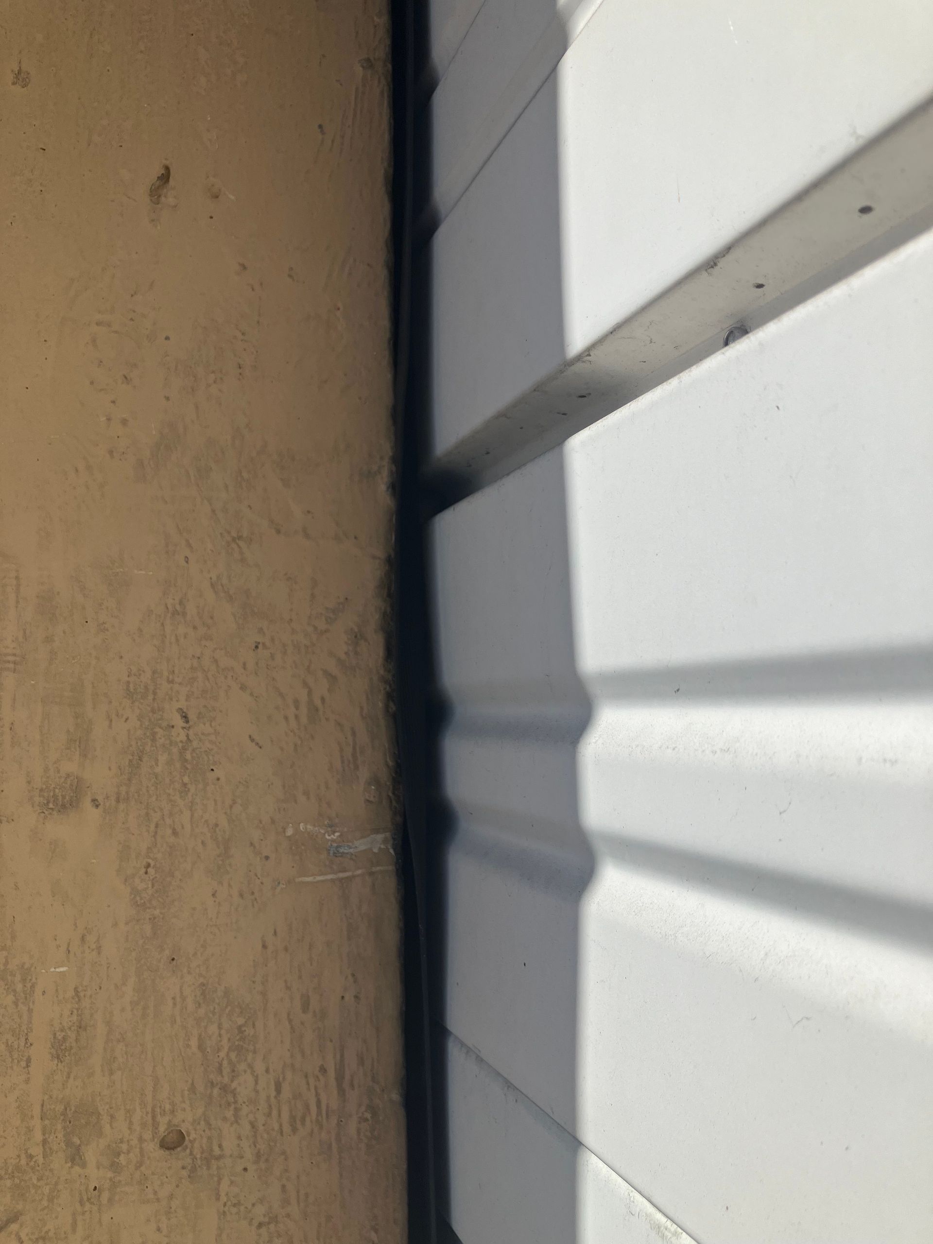 Close-up of a tan wall beside white horizontal blinds with sunlight casting shadows