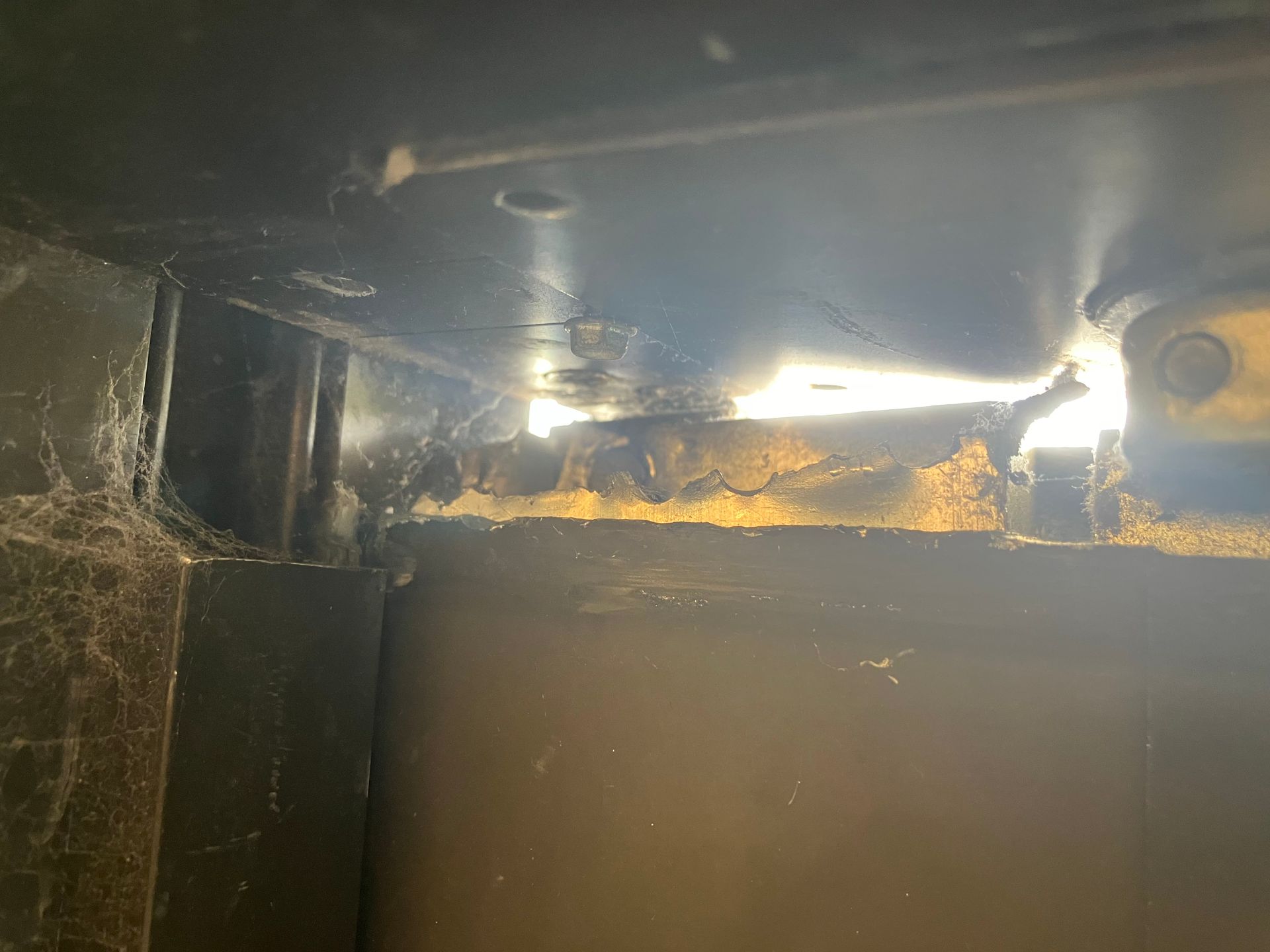 Dim, rusty metal interior with cobwebs and bright light reflecting off the top edge