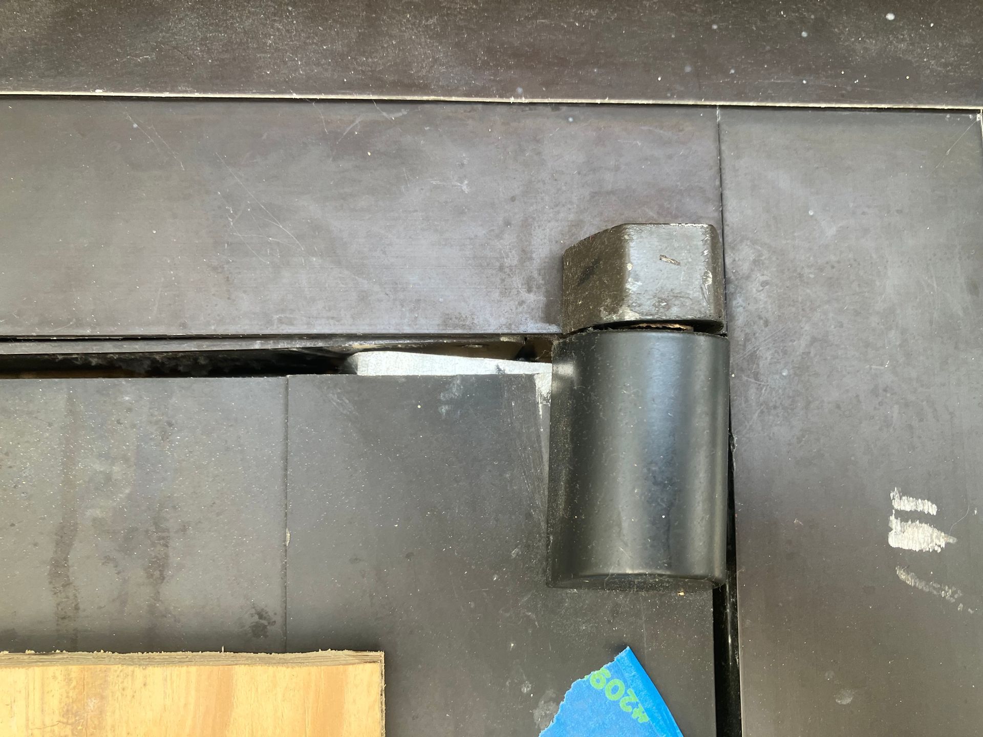 Close-up of a gray metal hinge or pipe joint on a dark wall.
