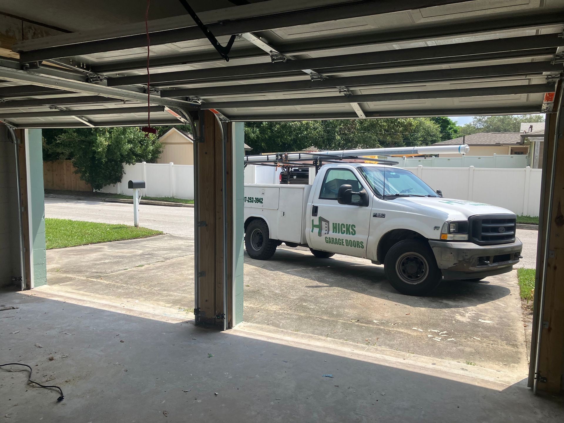 White work truck parked in a driveway, viewed from inside a garage.