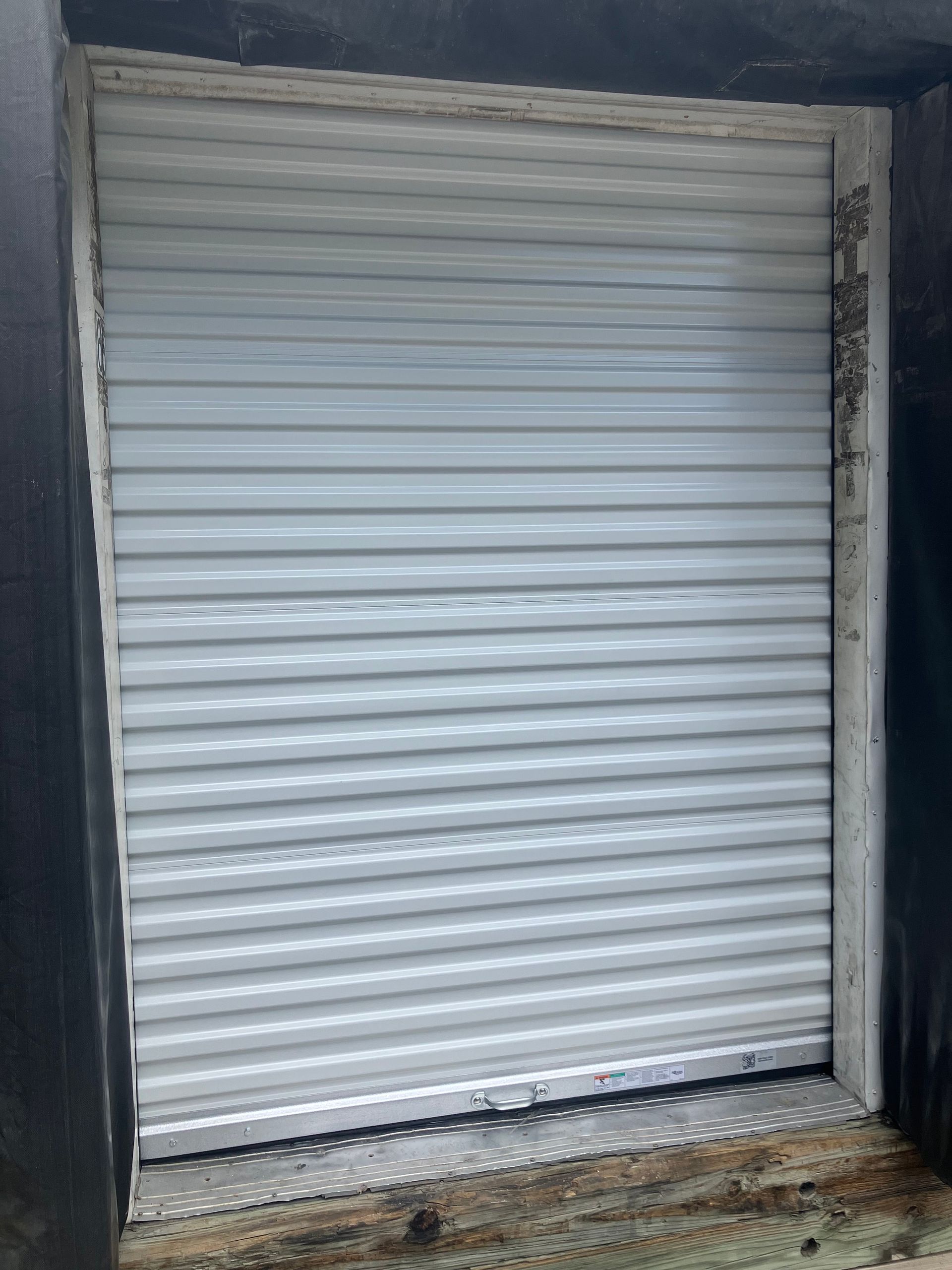 Closed white metal roll-up shutter on a storefront entrance