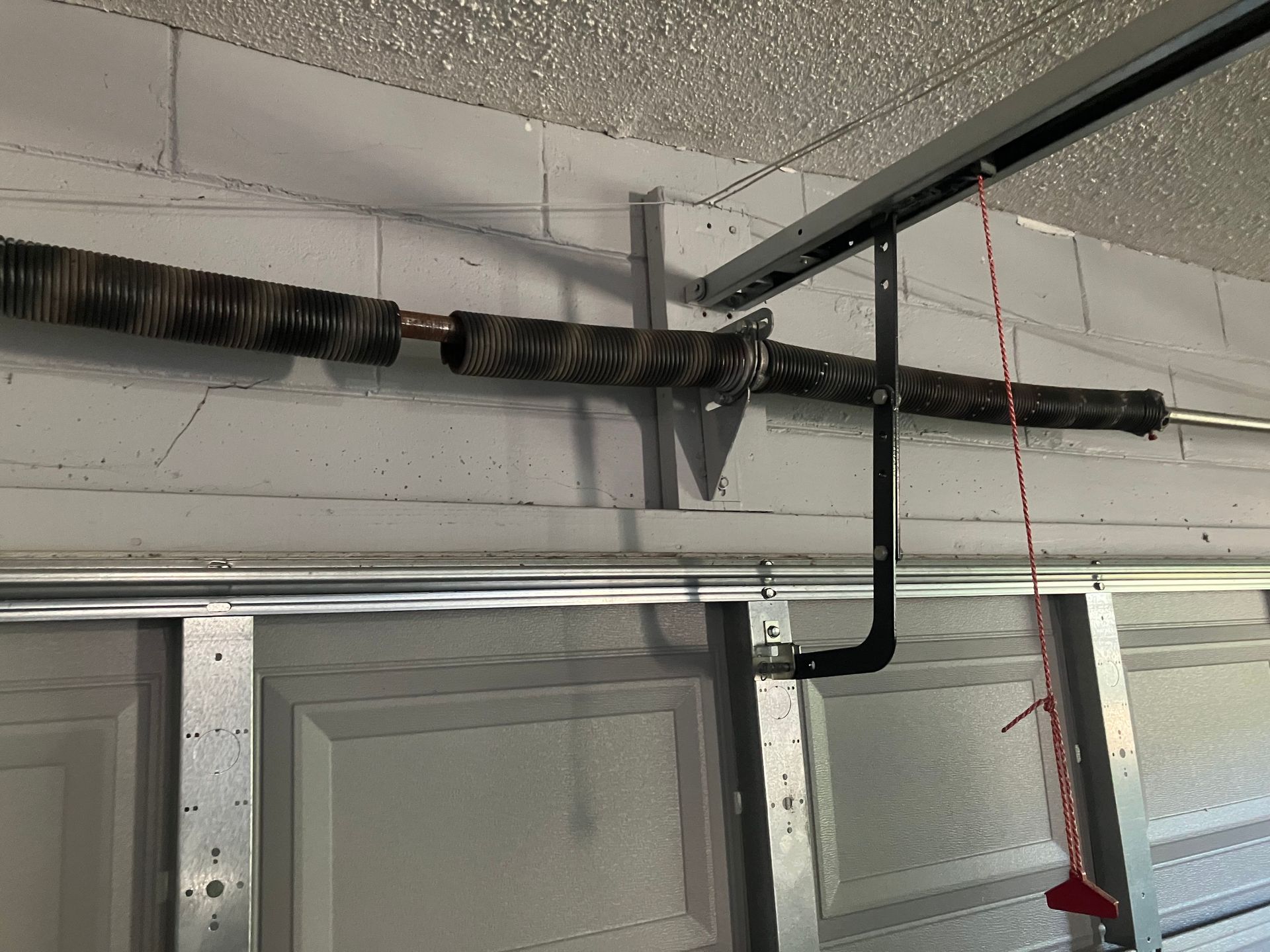 Garage ceiling with a damaged black pipe or duct hanging above a garage door.