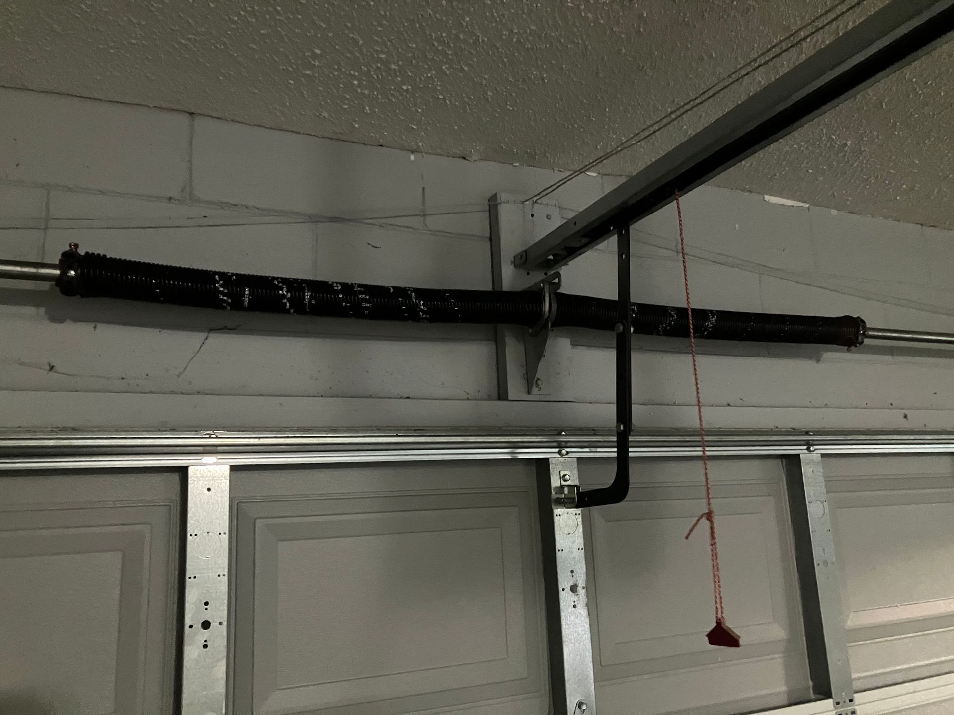 Garage ceiling with black insulated pipe and a red pull cord above a door