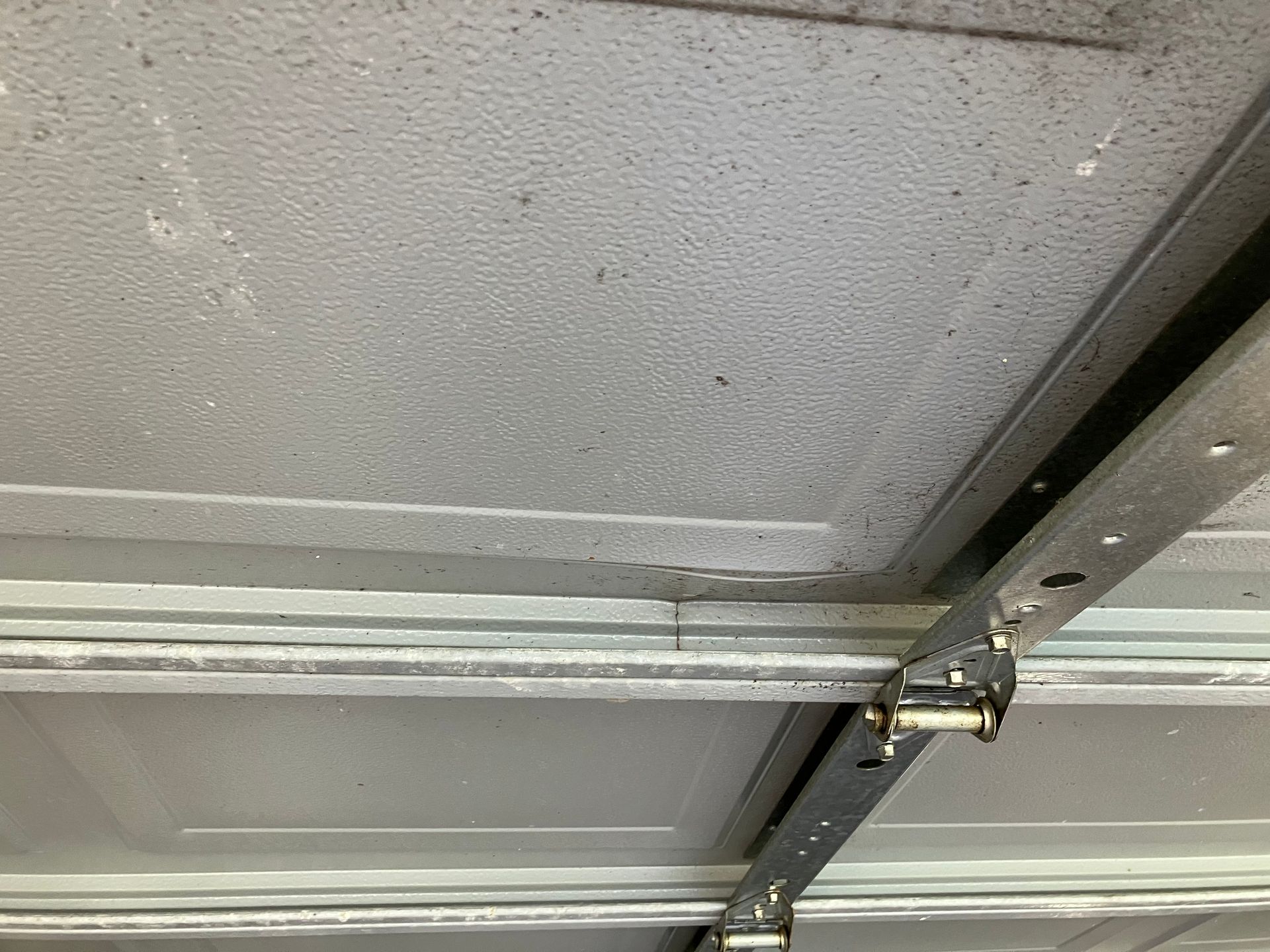 Close-up of a garage door panel with metal support struts and a hinge bracket.