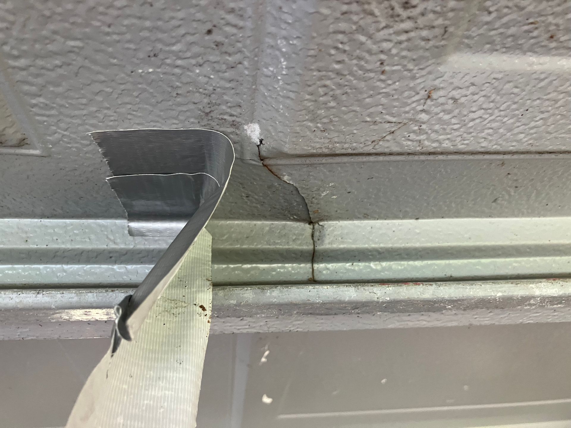 Close-up of a damaged taped seam on a gray ceiling panel or wall joint