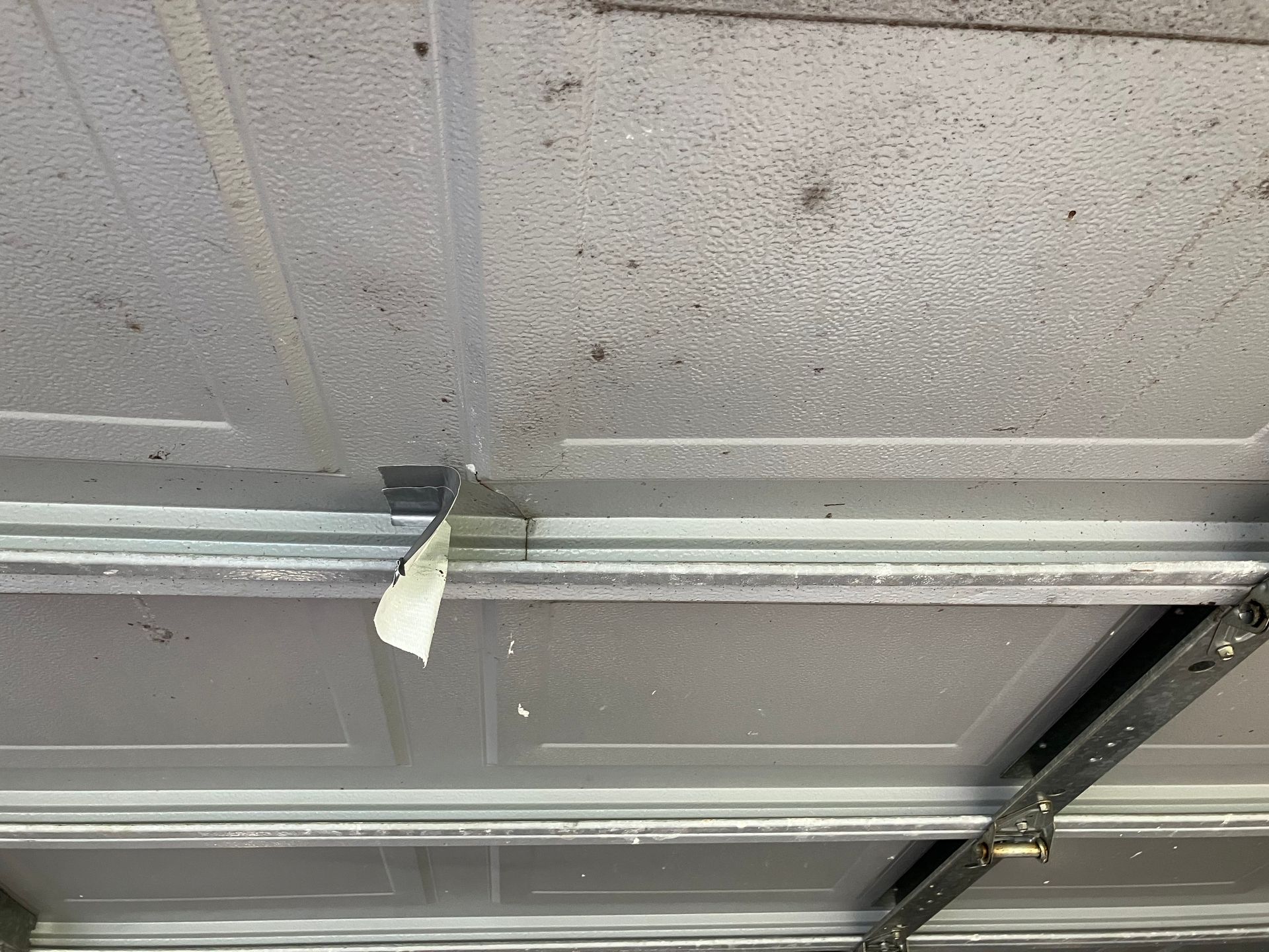 Ceiling tiles in a room, with a loose strip hanging from the metal grid.