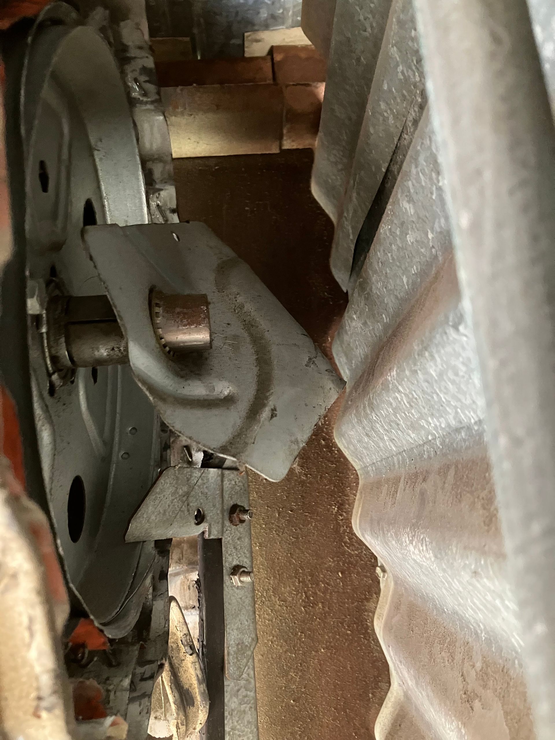 Close-up of a metal machine part with a gray bracket beside a silver, textured panel.