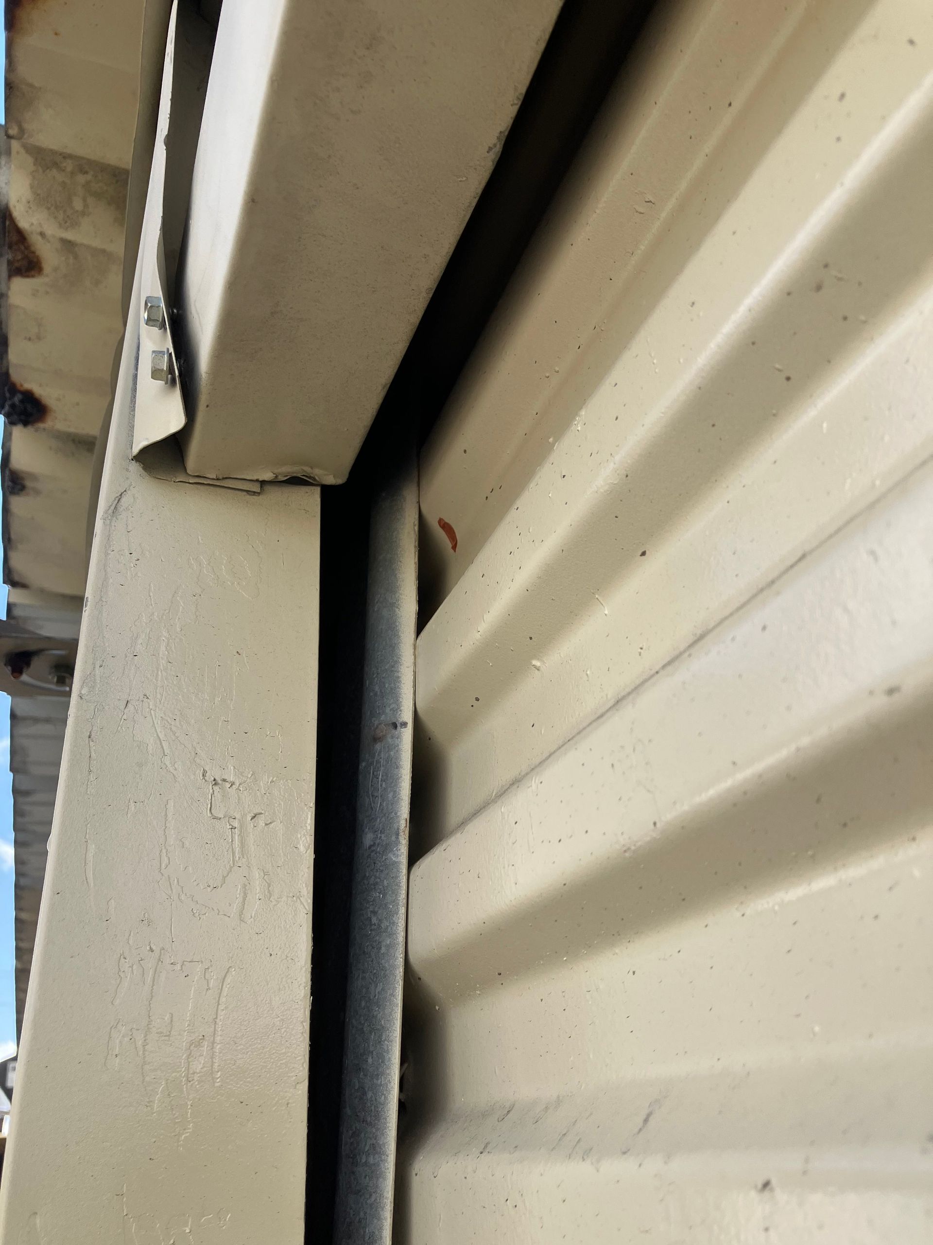 Close-up of beige house siding and trim with a narrow vertical gap between them