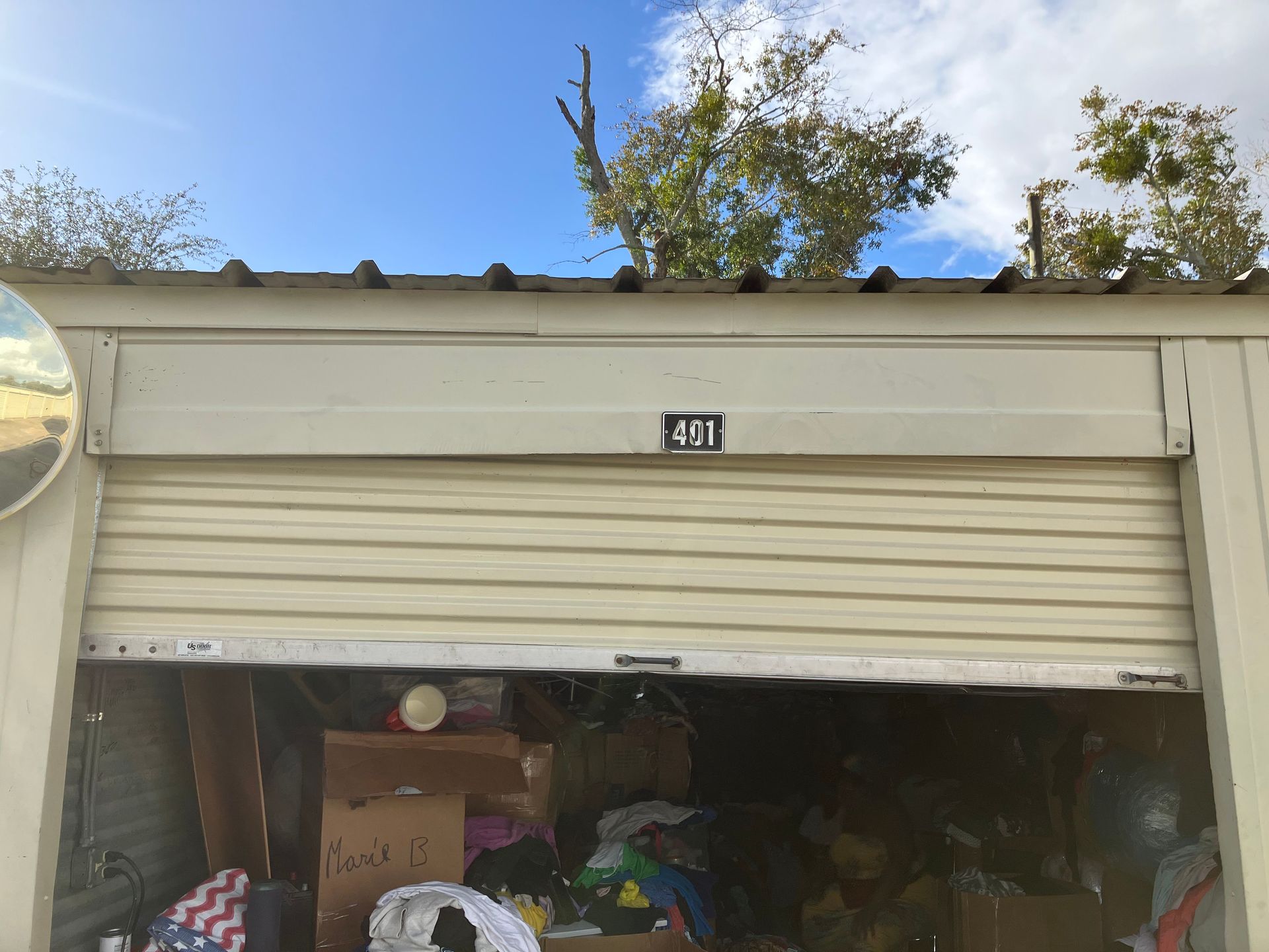 Open garage with cluttered interior, partially closed roll-up door, and house number 401 above.