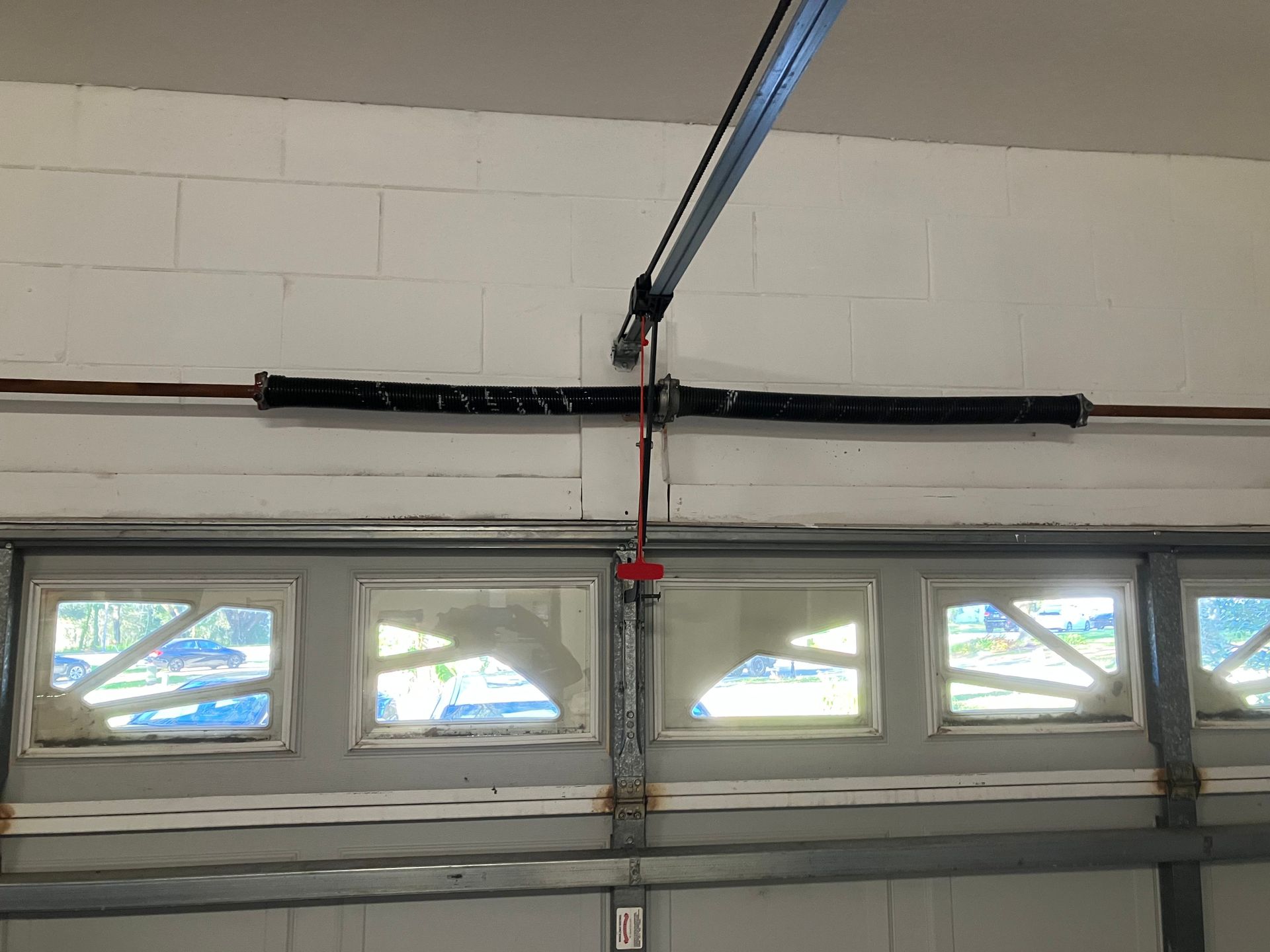 Garage door with a black opener rail and small frosted windows near the top.