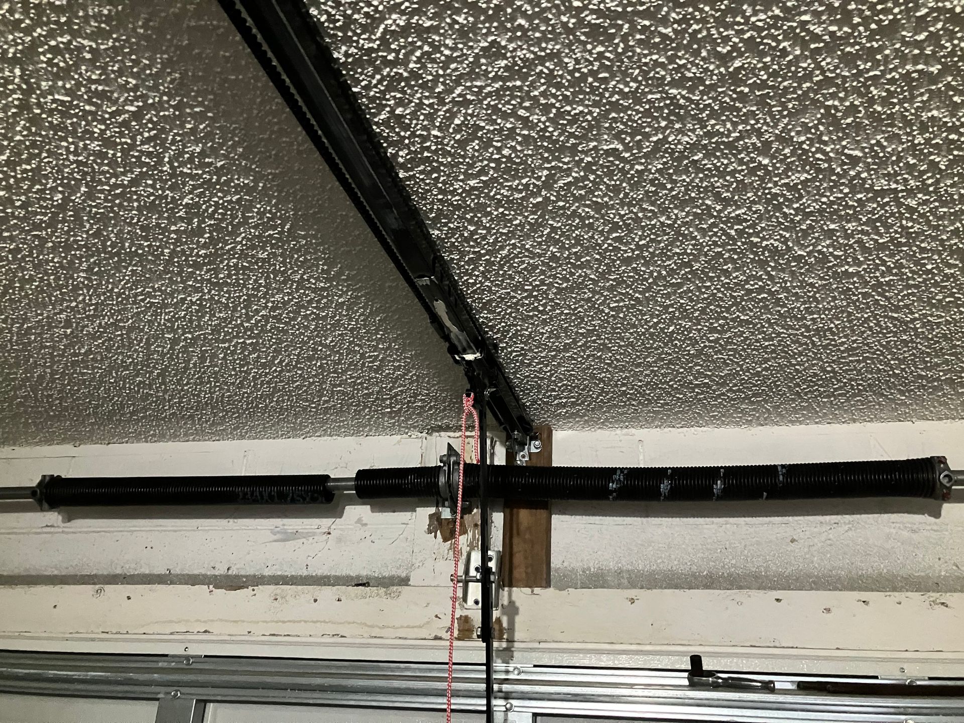 Ceiling garage door opener track with a centered broken cable and hanging wires