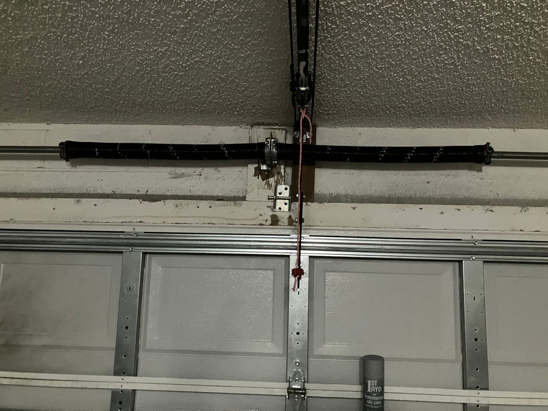 Garage ceiling with a black garage door opener and hanging red pull cord above a closed door